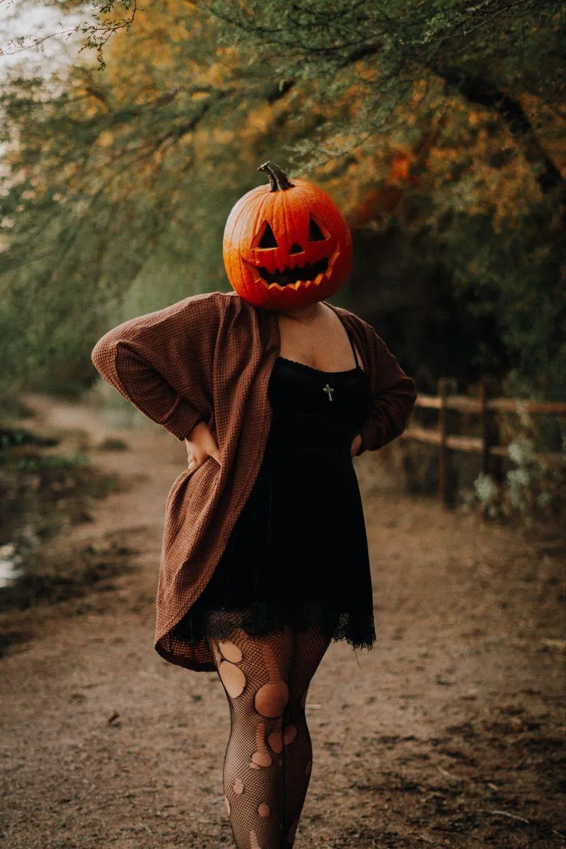 Women in Elegant Pumpkin Head Costume in Autumn Setting