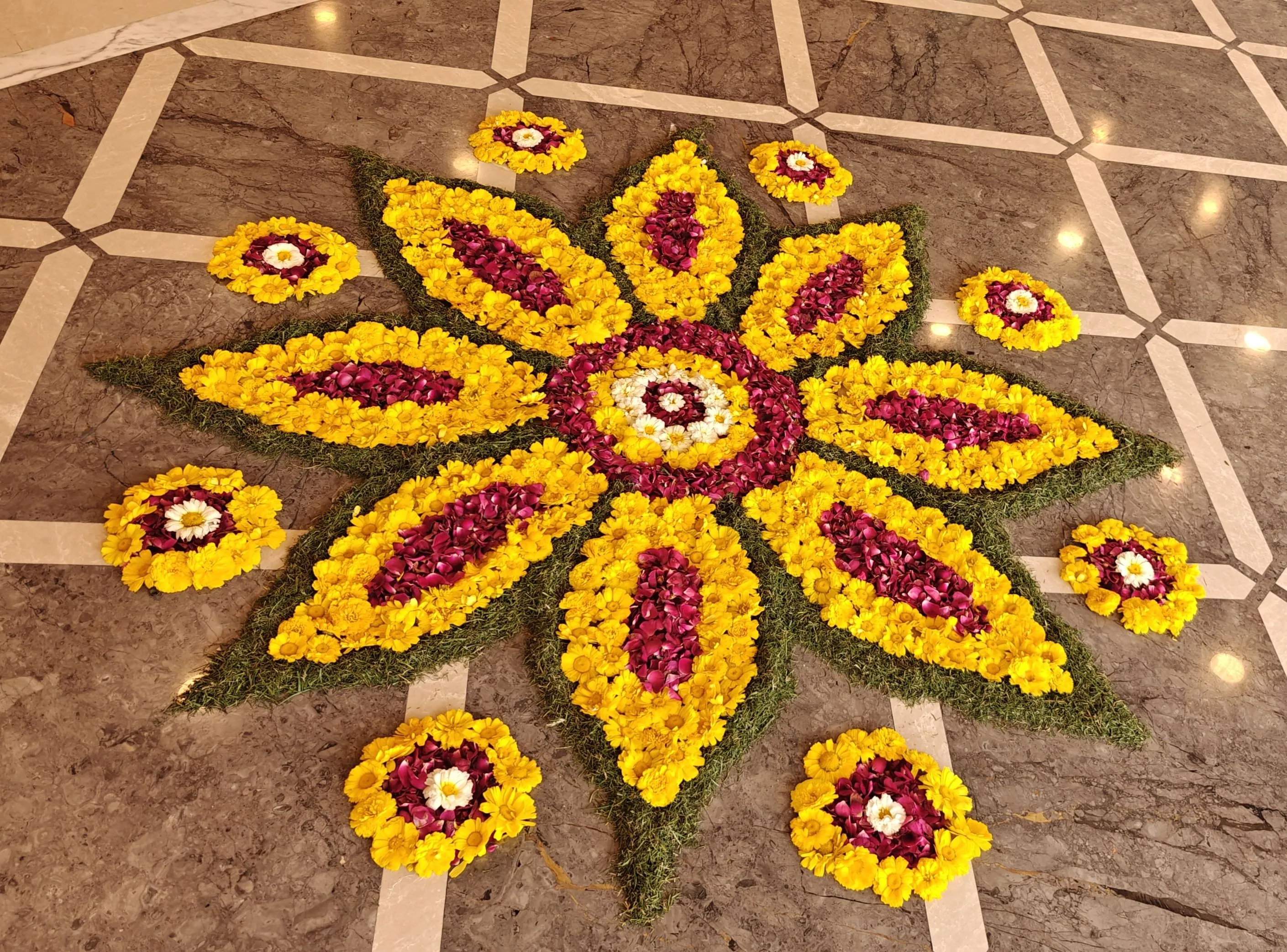 Yellow and pink floral pookolam on marble floor HD image