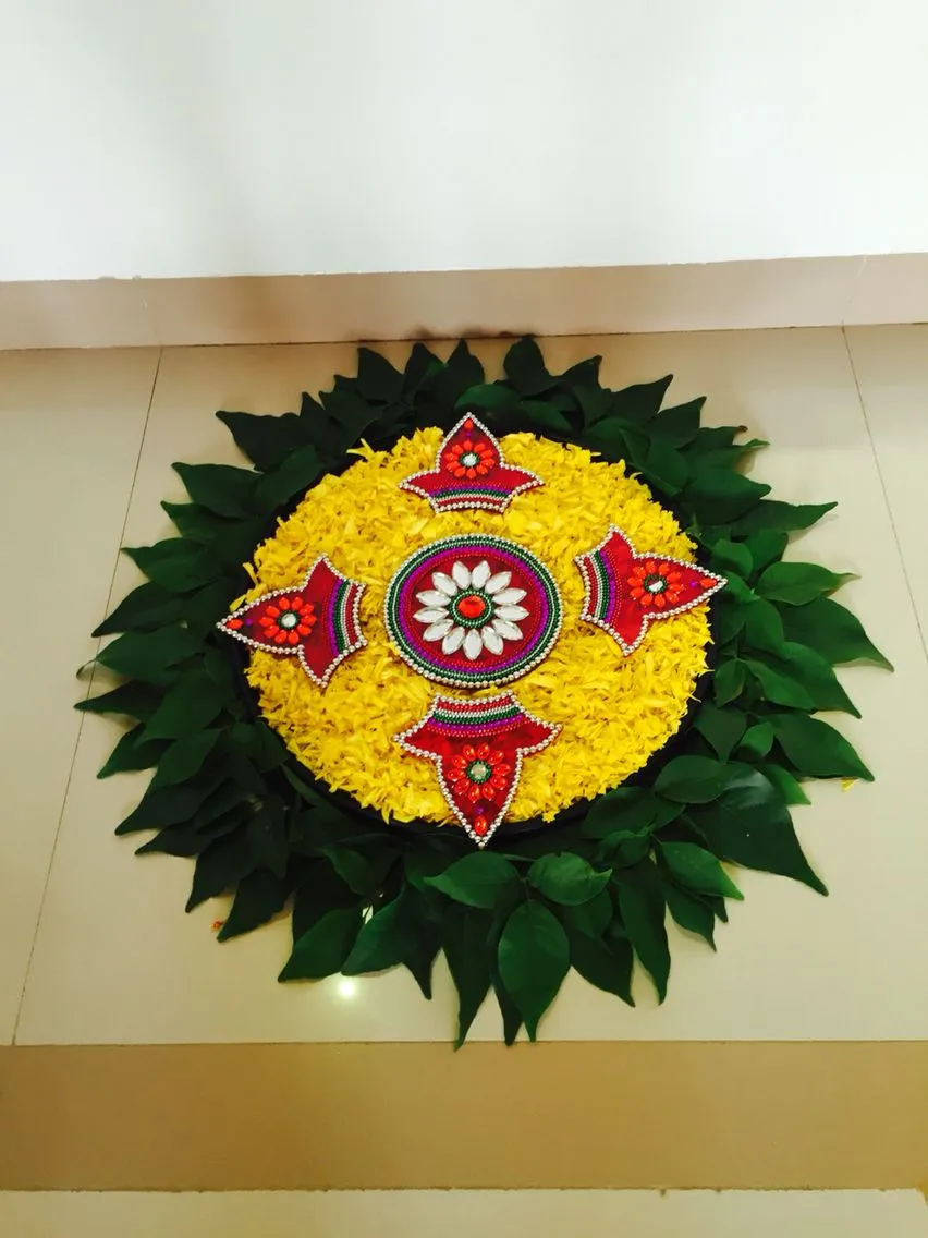 Yellow circular pookolam with beads and a fresh leaf borders
