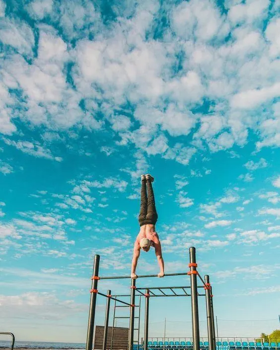 Athlete Performing a Handstand on Bars With a Blue Sky