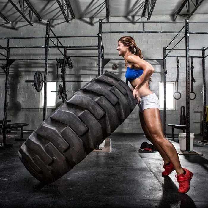 Athletic Woman Flipping Giant Tire in Crossfit Gym Wallpaper
