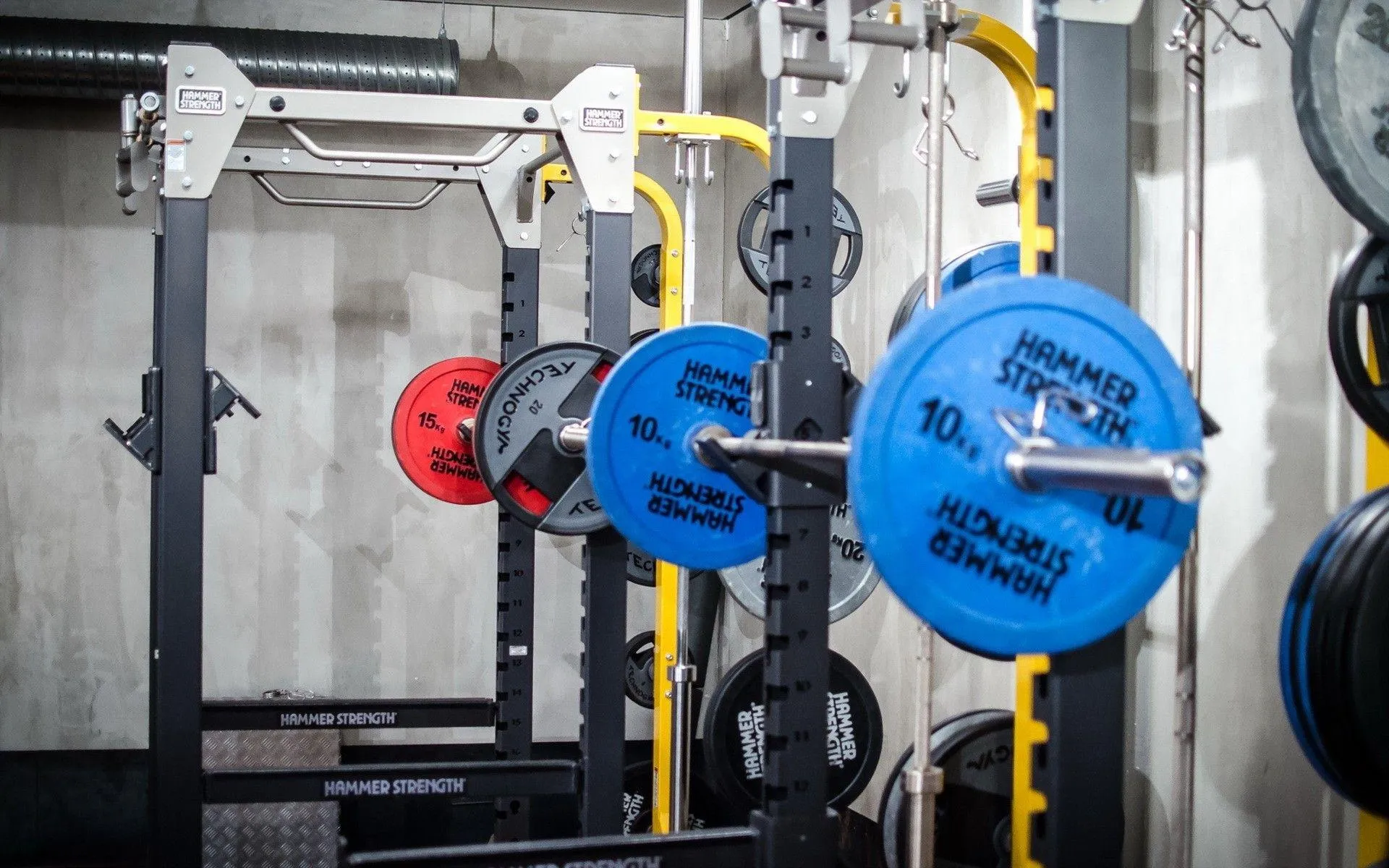 Barbell Loaded With Blue Weight Plates in Gym Rack Wallpaper