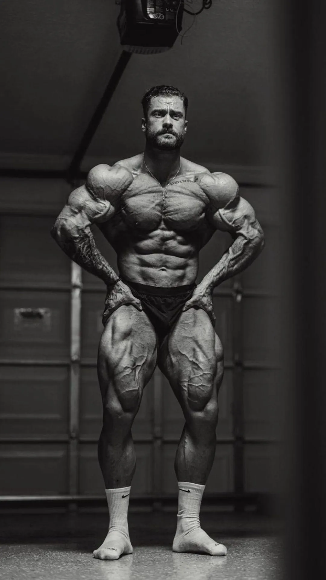 Black and White Photo of Chris Bumstead Posing in a Gym