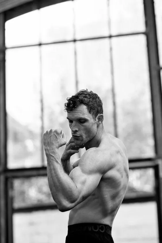 Black and White Photo of a Shirtless Man Flexing Muscles