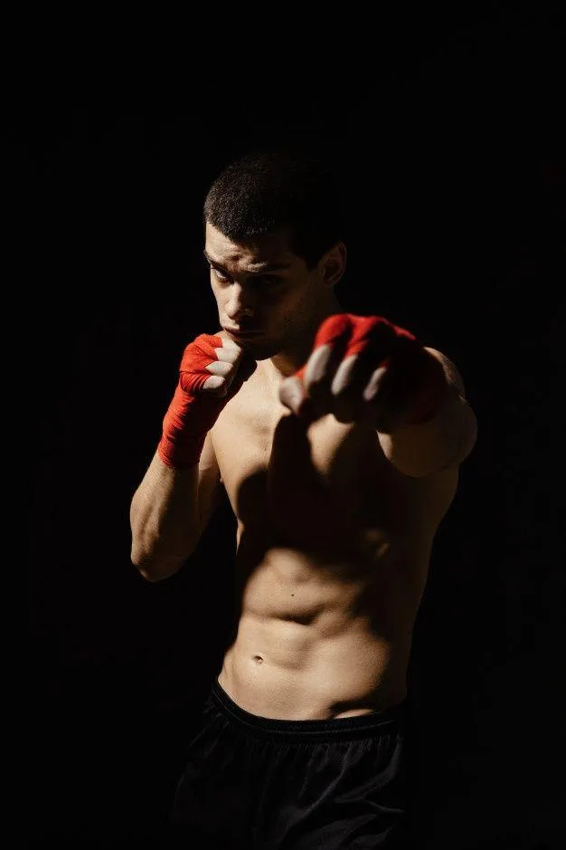 Boxer in a Dark Studio Posing With Red Gloves Before a Fight