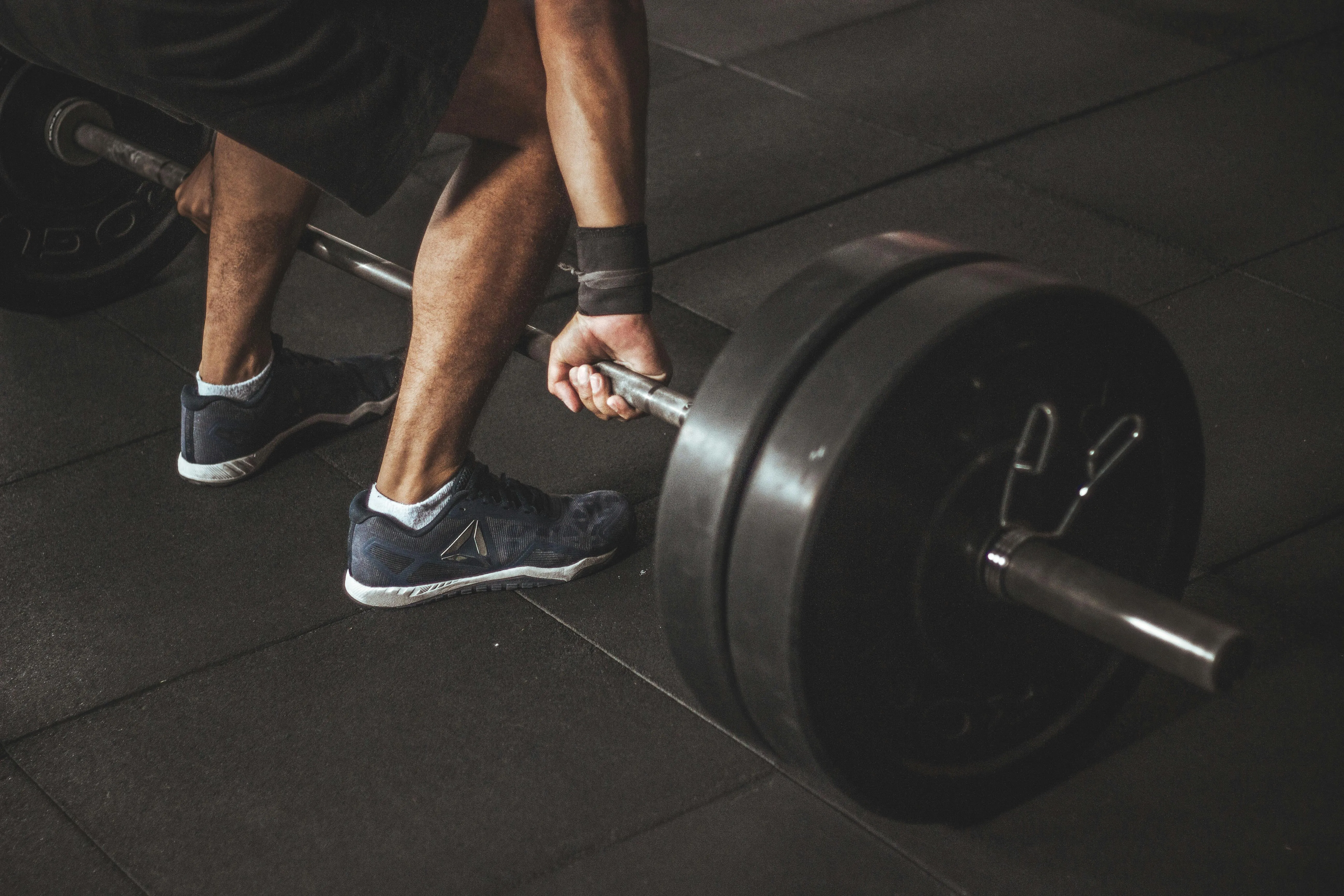 Close Up of Feet Lifting a Barbell From the Gym Floor
