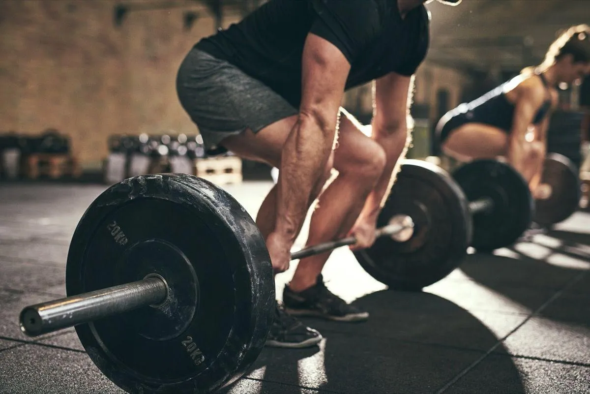 Close Up of a Man Lifting Heavy Barbell in a Gym Environment