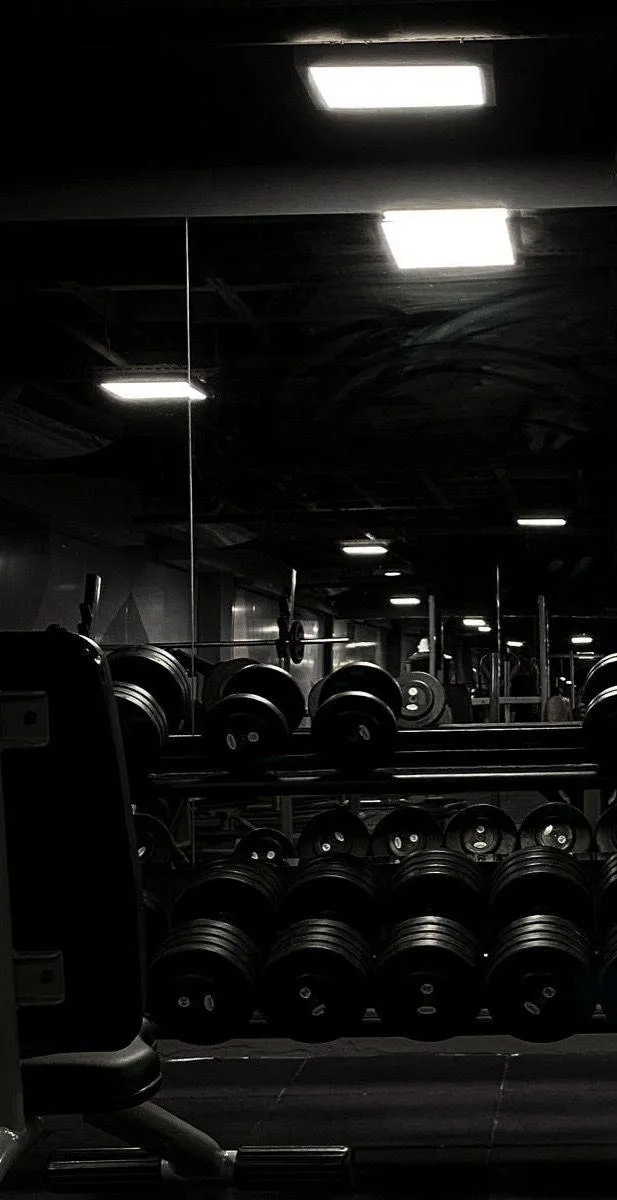 Dumbbell Rack in a Dimly Lit Gym With Mirror Reflections