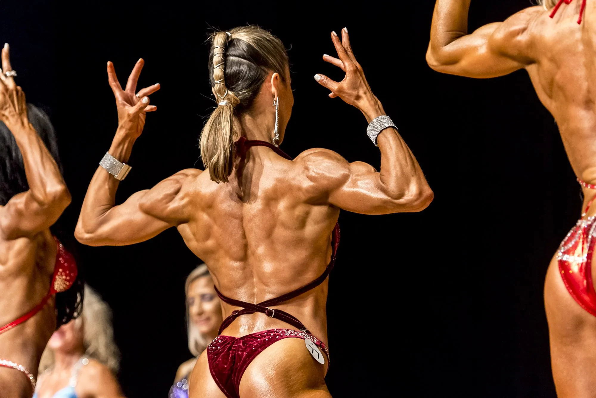 Female Bodybuilder Flexing Back Muscles on Stage Wallpaper