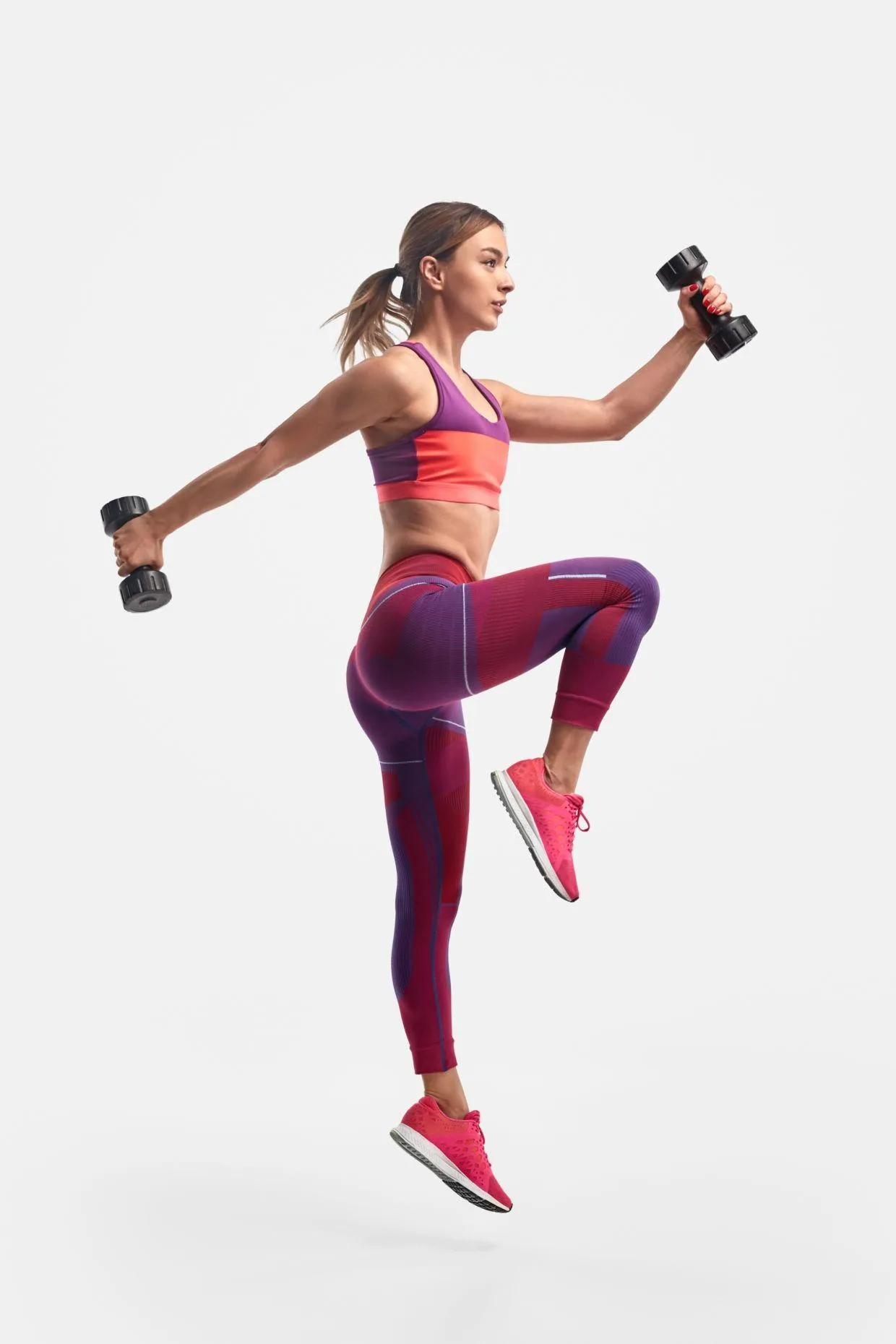 Fit Woman Jumping With Dumbbells During a Workout Wallpaper