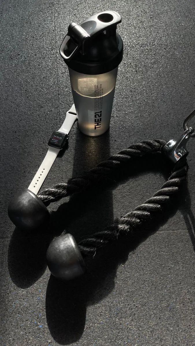 Gym Rope and Shaker Bottle Placed on a Dark Gym Floor