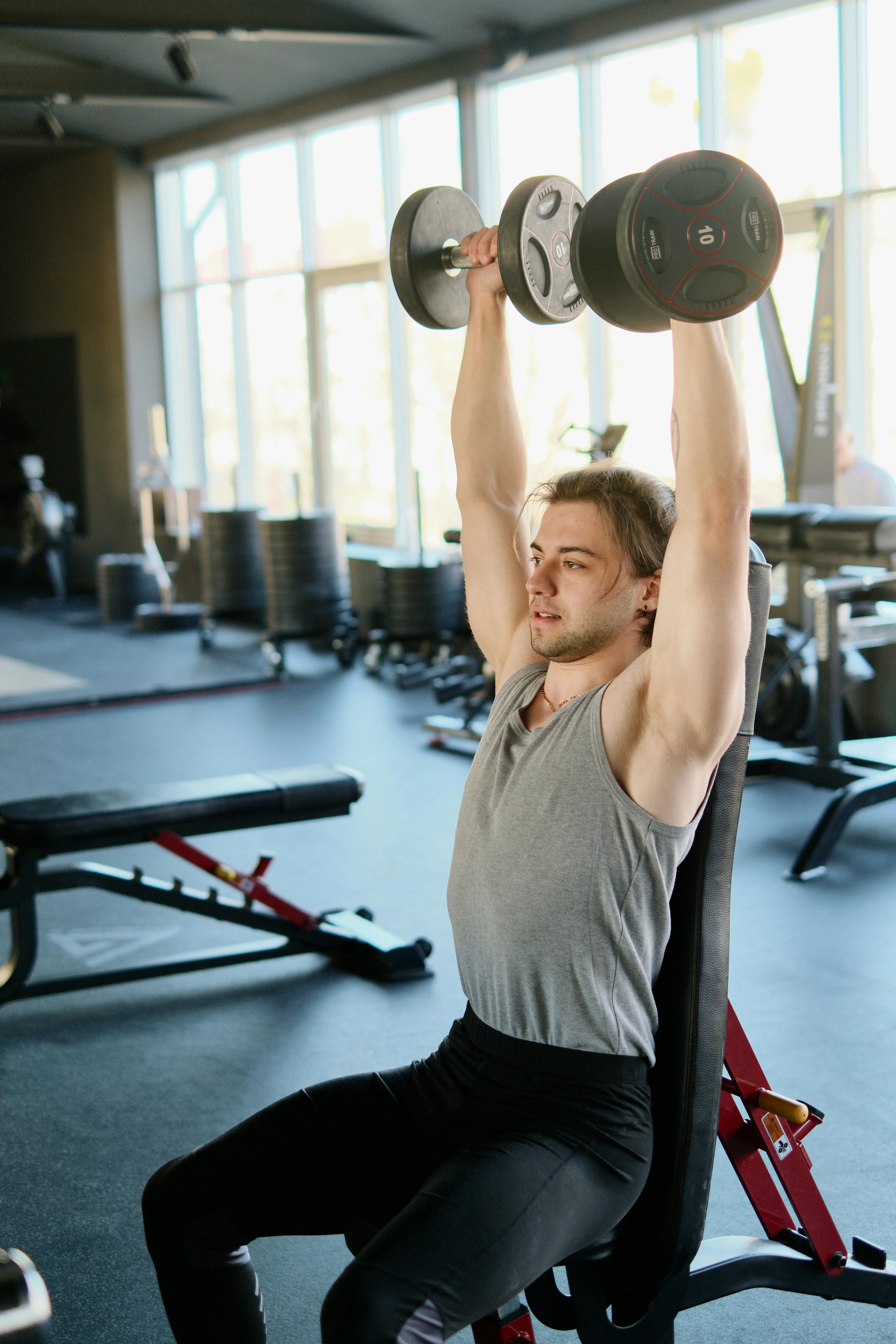 Man Doing Dumbbell Shoulder Press While Seated in Gym