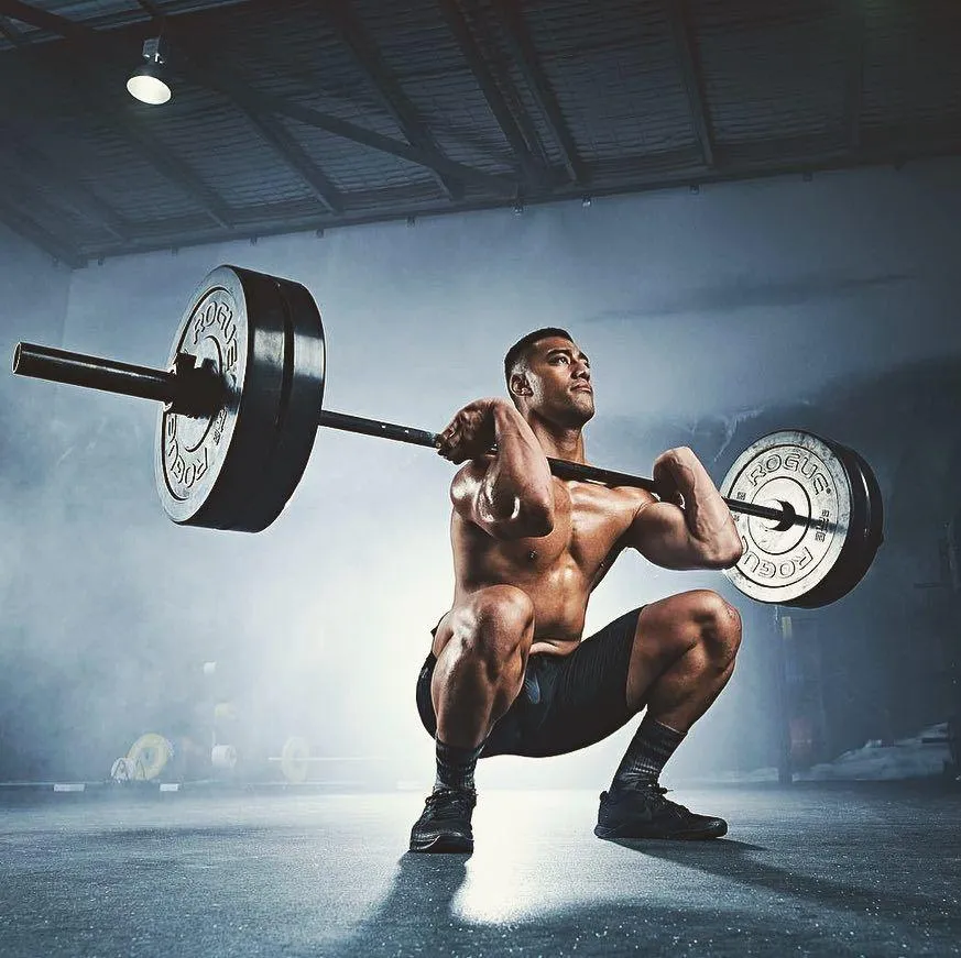 Man Doing Heavy Barbell Squats in a Darkly Lit Gym Wallpaper