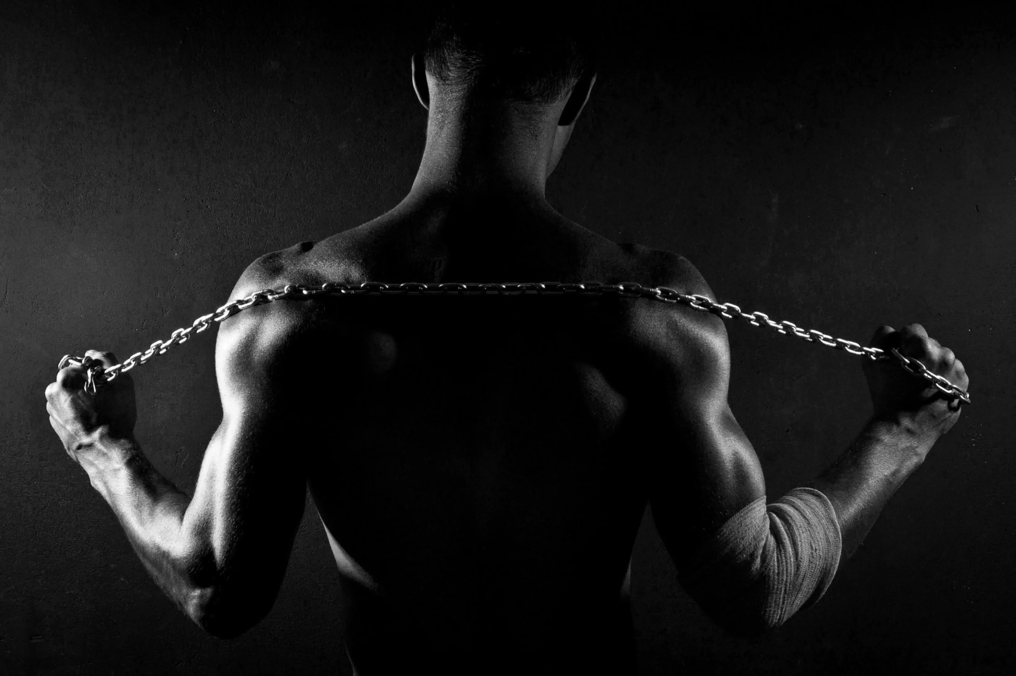 Man Holding Chain Behind Back Showing Muscular Fitness Pose