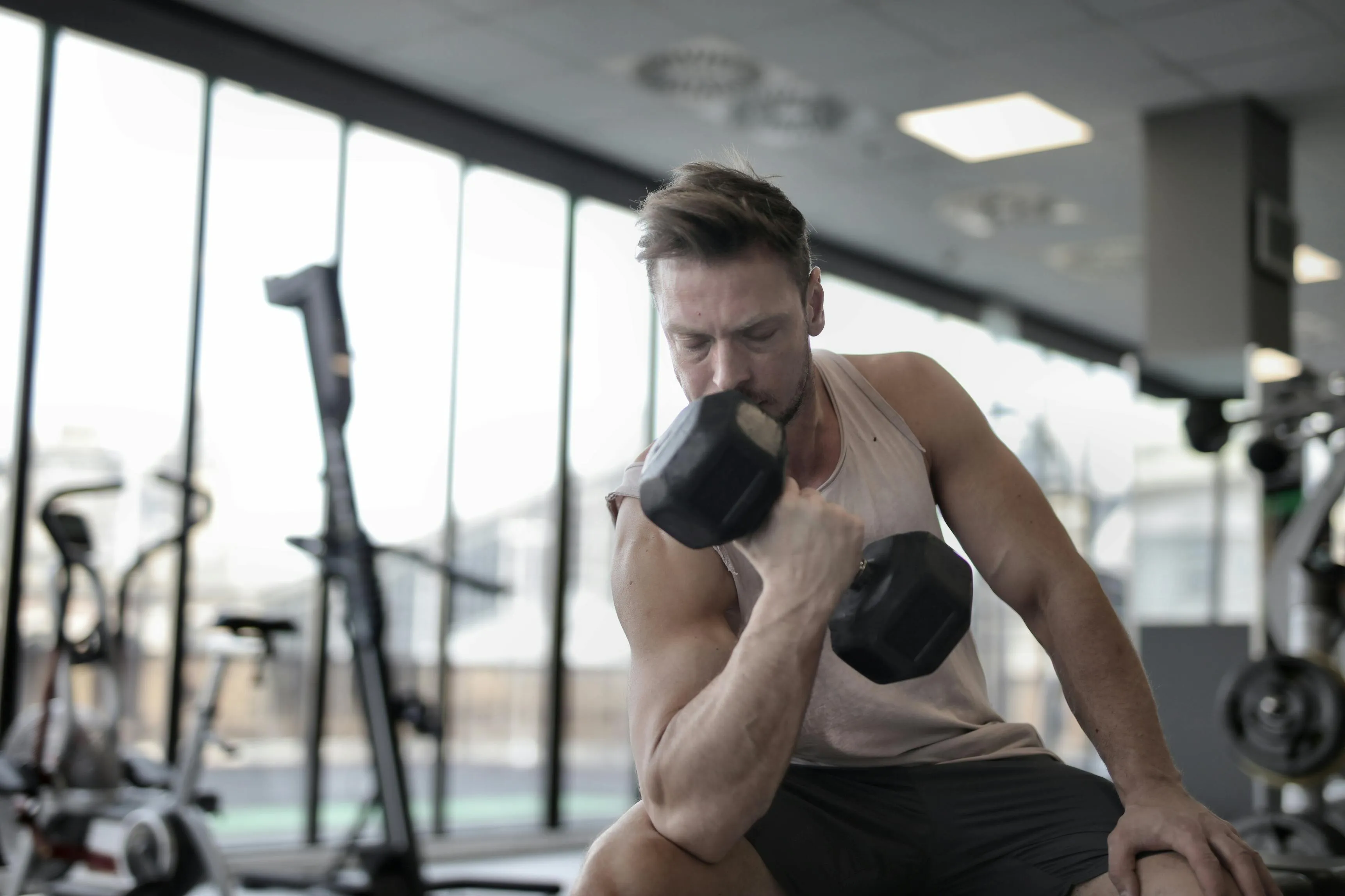 Man Is Doing Concentration Curls With a Dumbbell At the Gym