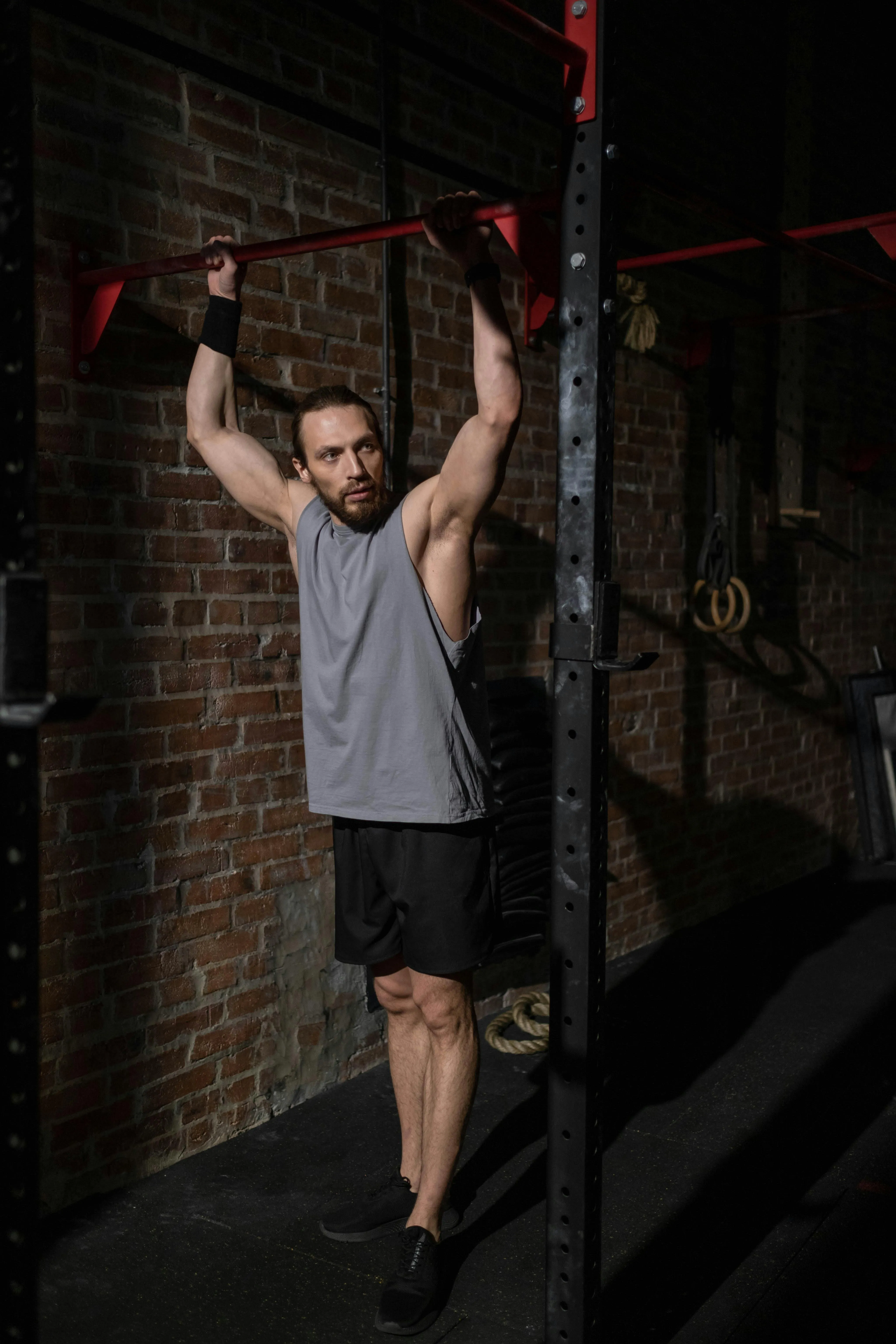 Man Lifting a Barbell For Squats Under a Red Gym Squat Rack