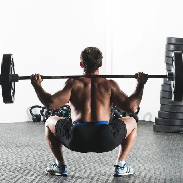 Man Performing a Barbell Squat With Weights in a Gym Session