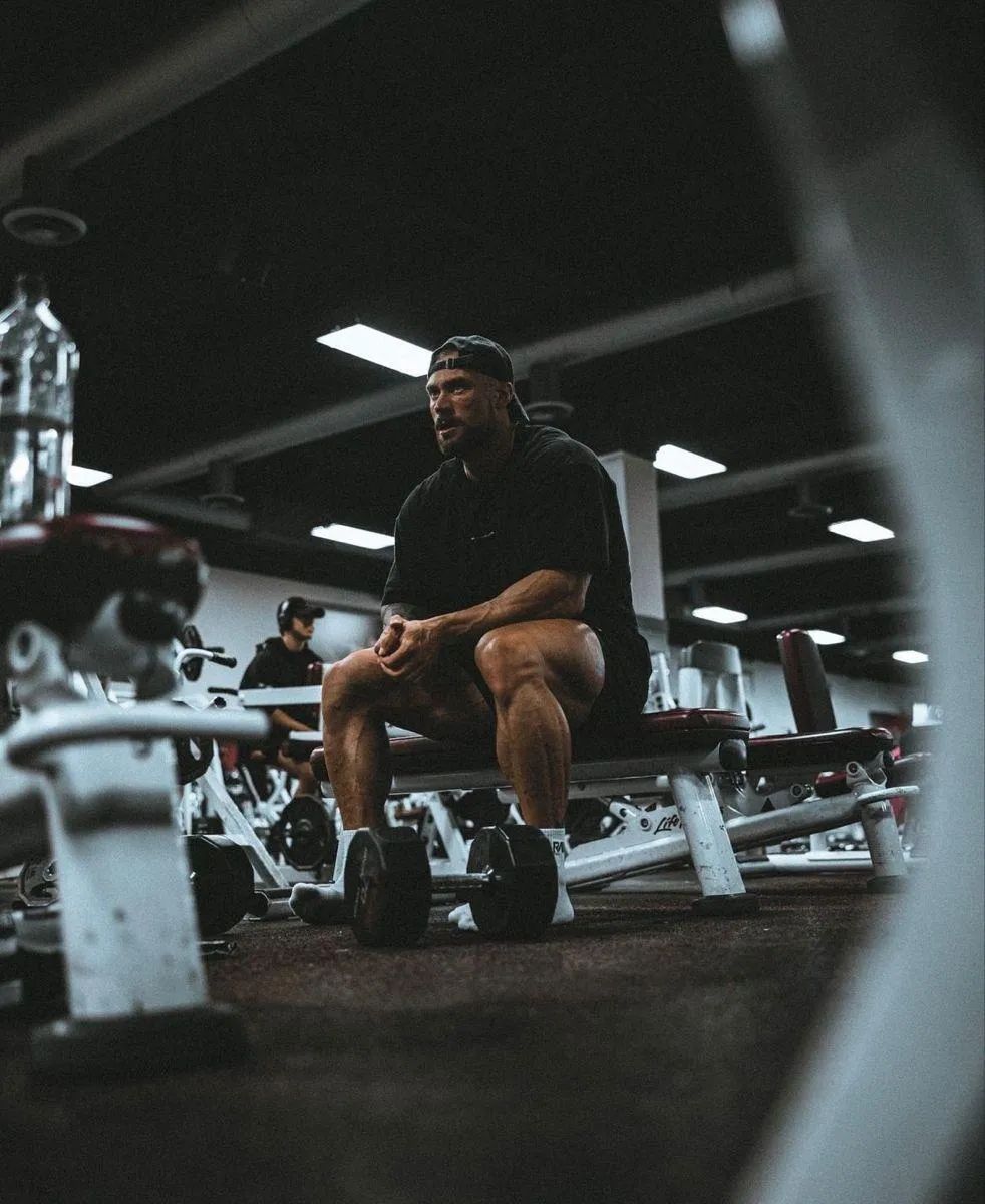 Man Resting on a Bench in the Gym Between Weightlifting Sets