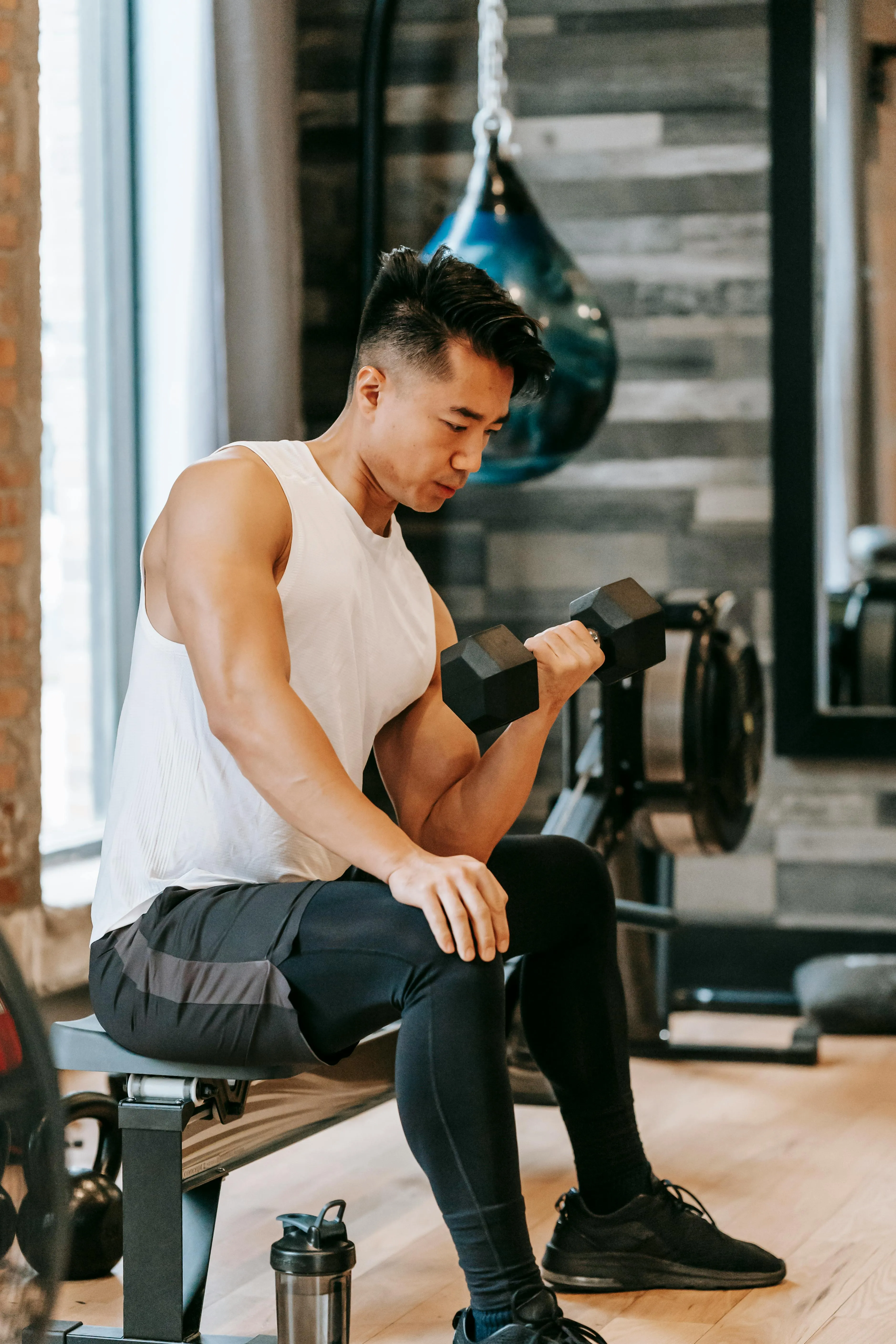 Man Seated Curling a Dumbbell With Focus in the Weight Room