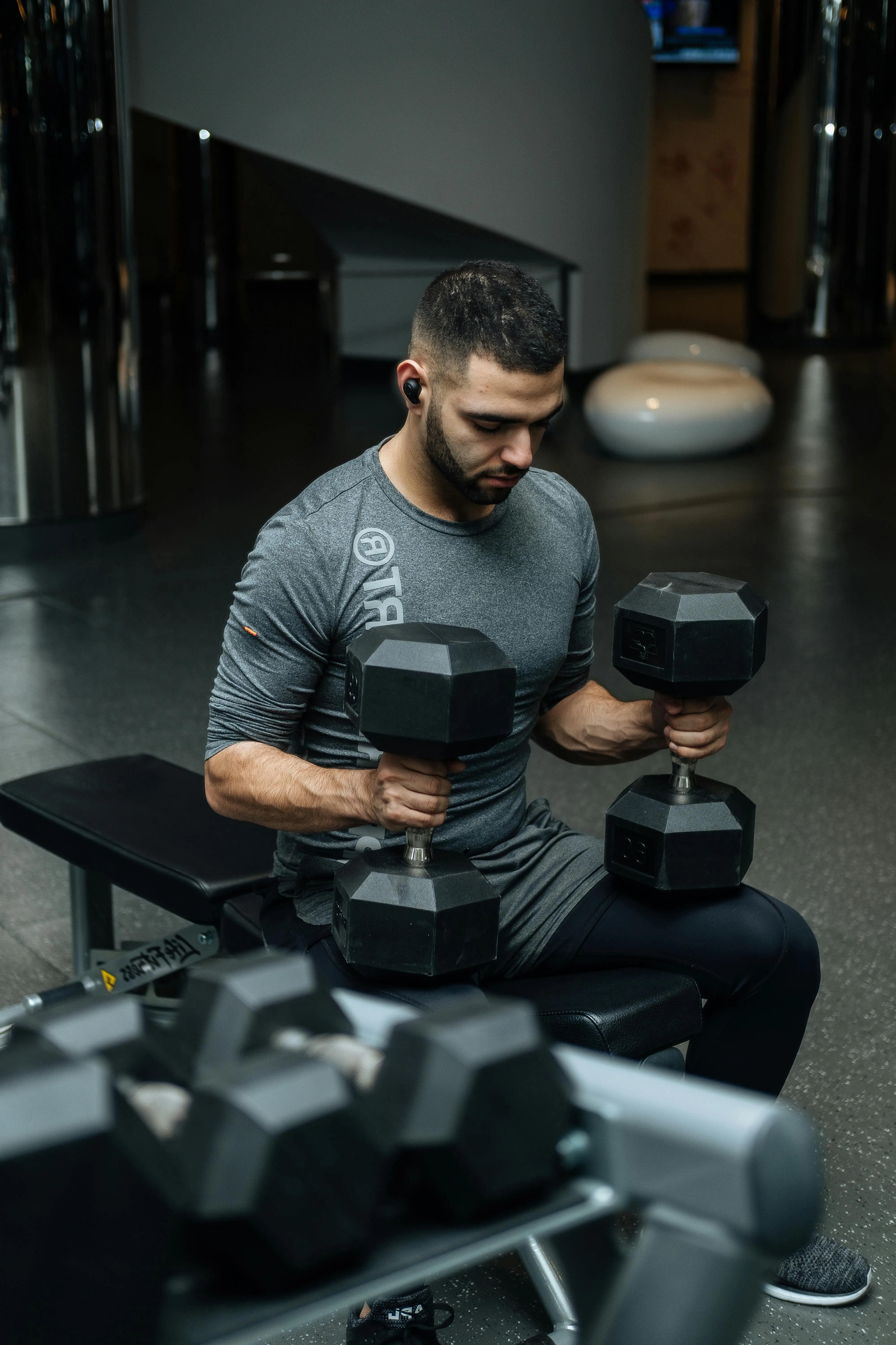 Man Sitting and Lifting Dumbbells During a Gym Arm Workout