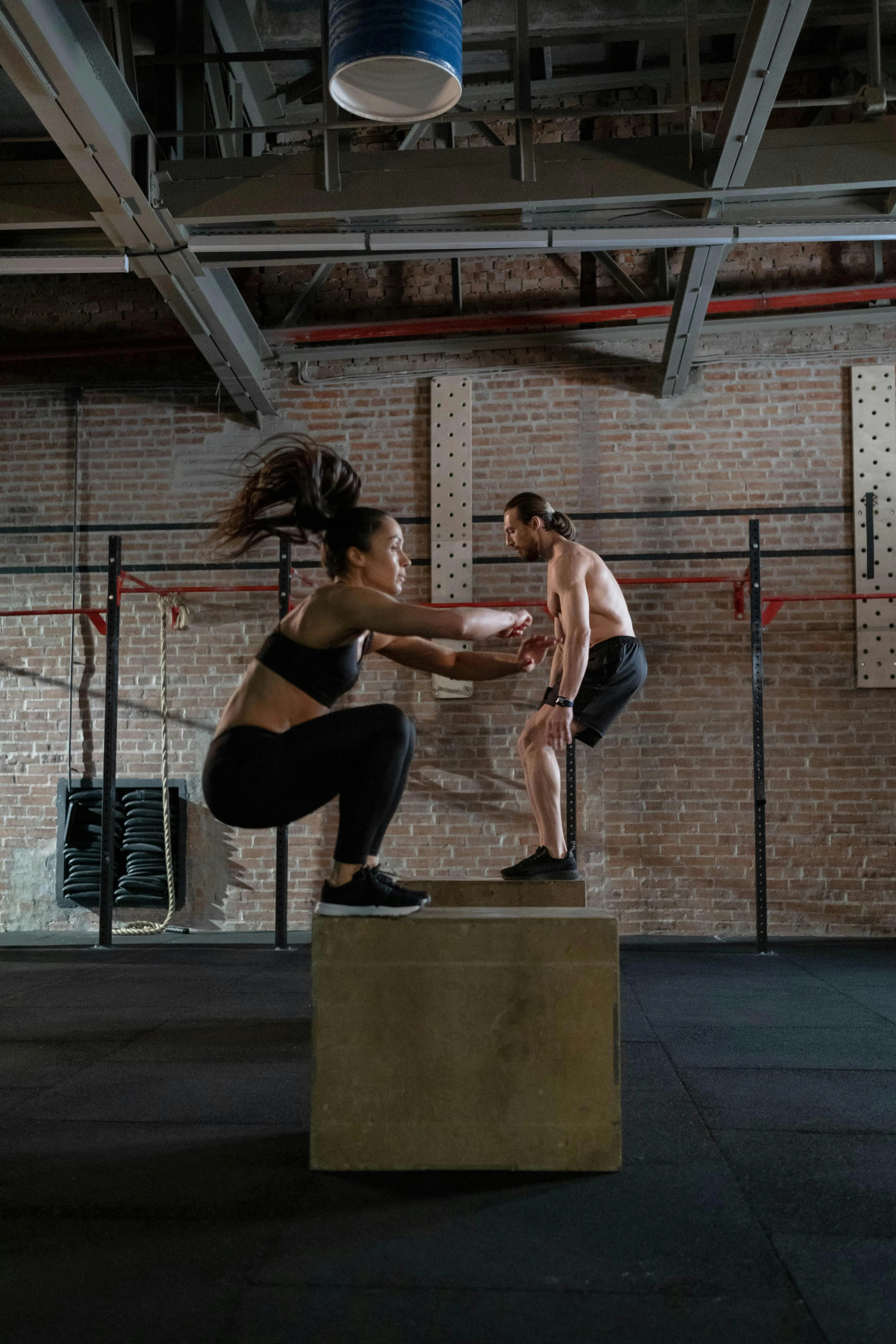 Man and a Woman Doing Box Jump Exercises Inside the Gym