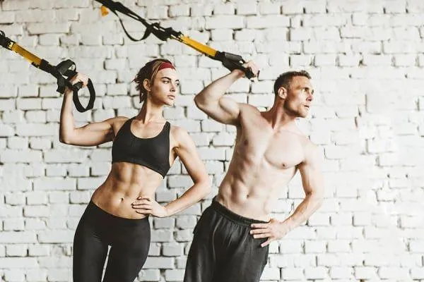 Man and Woman Doing Suspension Training on a White Wall