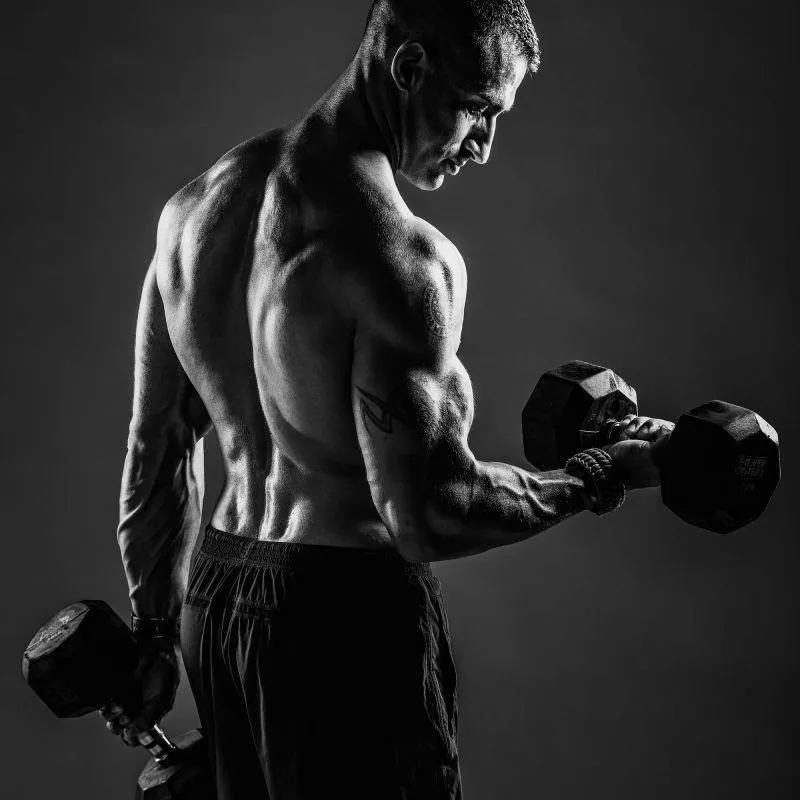 Muscular Man Lifting Dumbbells Showing Strong Back and Arms