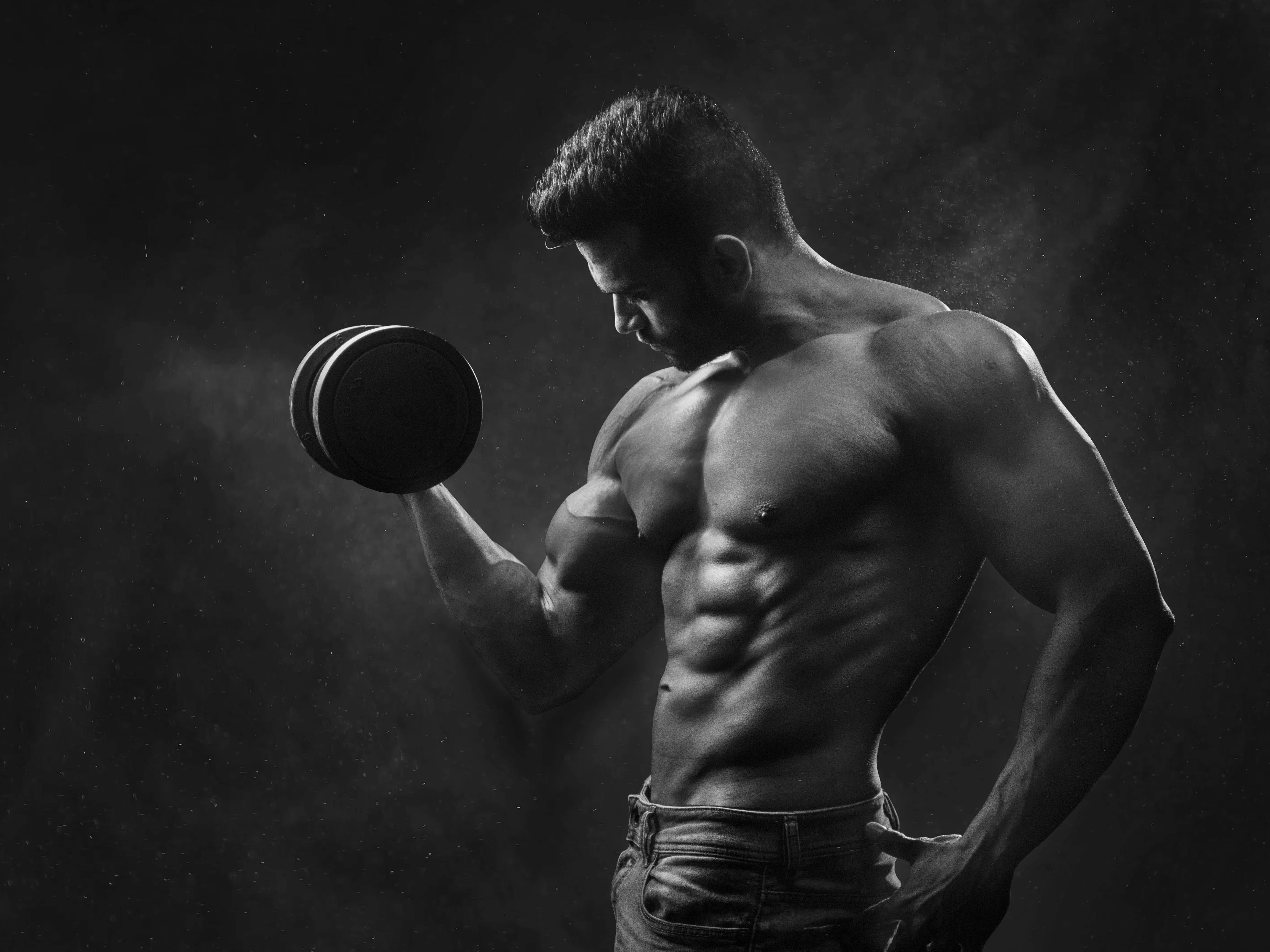 Muscular Man Posing With Dumbbell in Black and White Photo