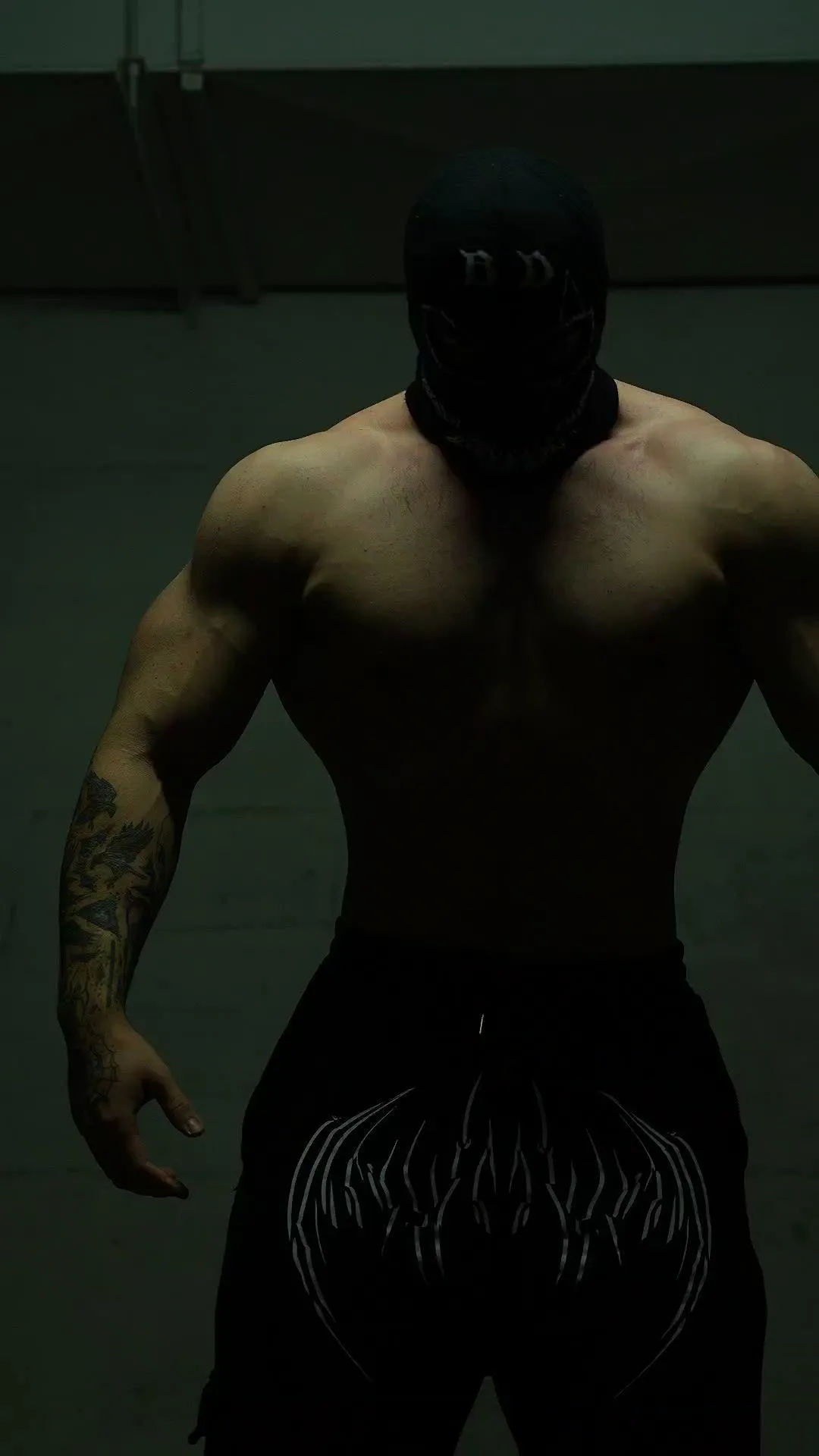 Muscular Man Wearing a Dark Mask Standing in a Shadowy Gym