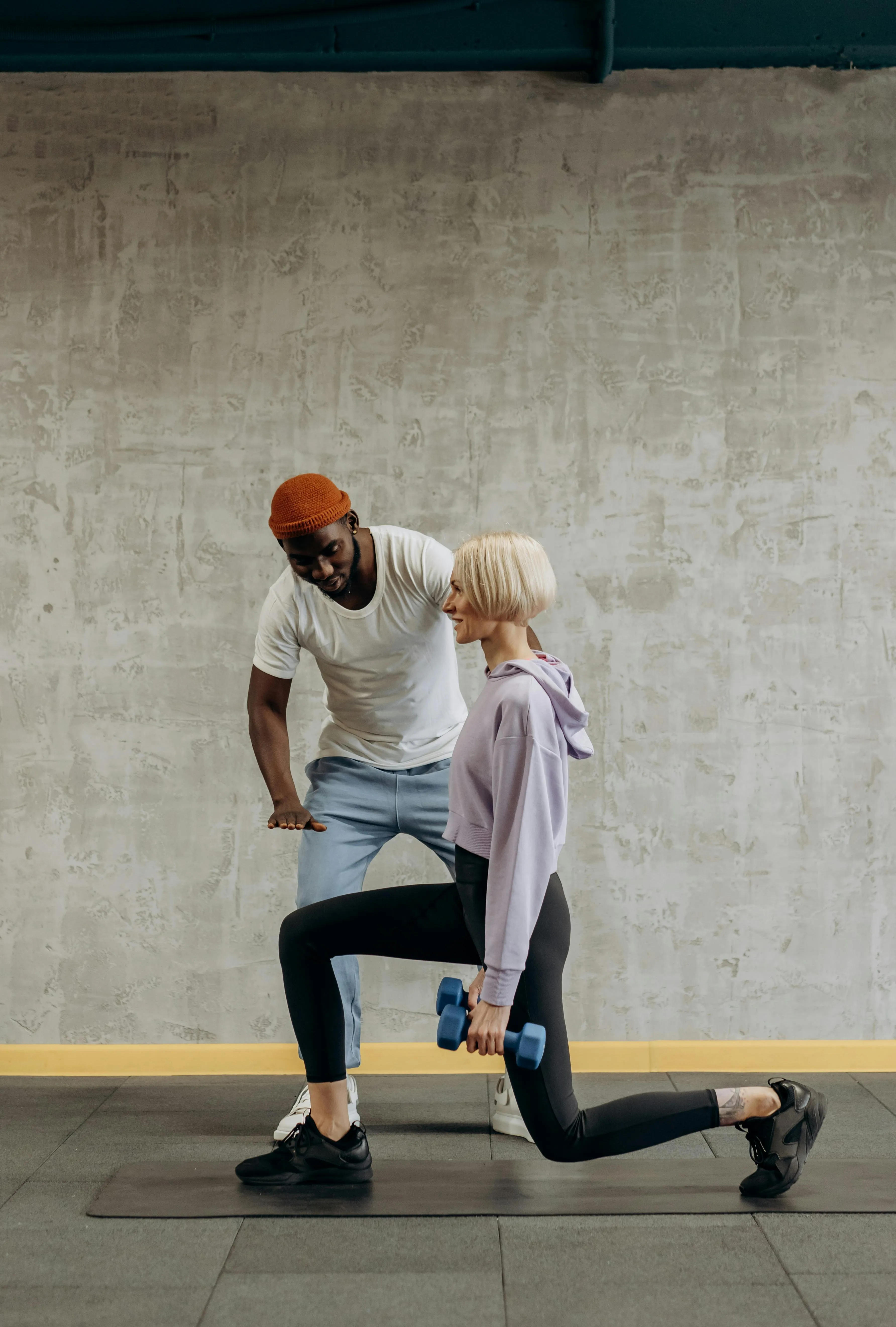 Personal Trainer Helping Woman With Assisted Lunge Reps