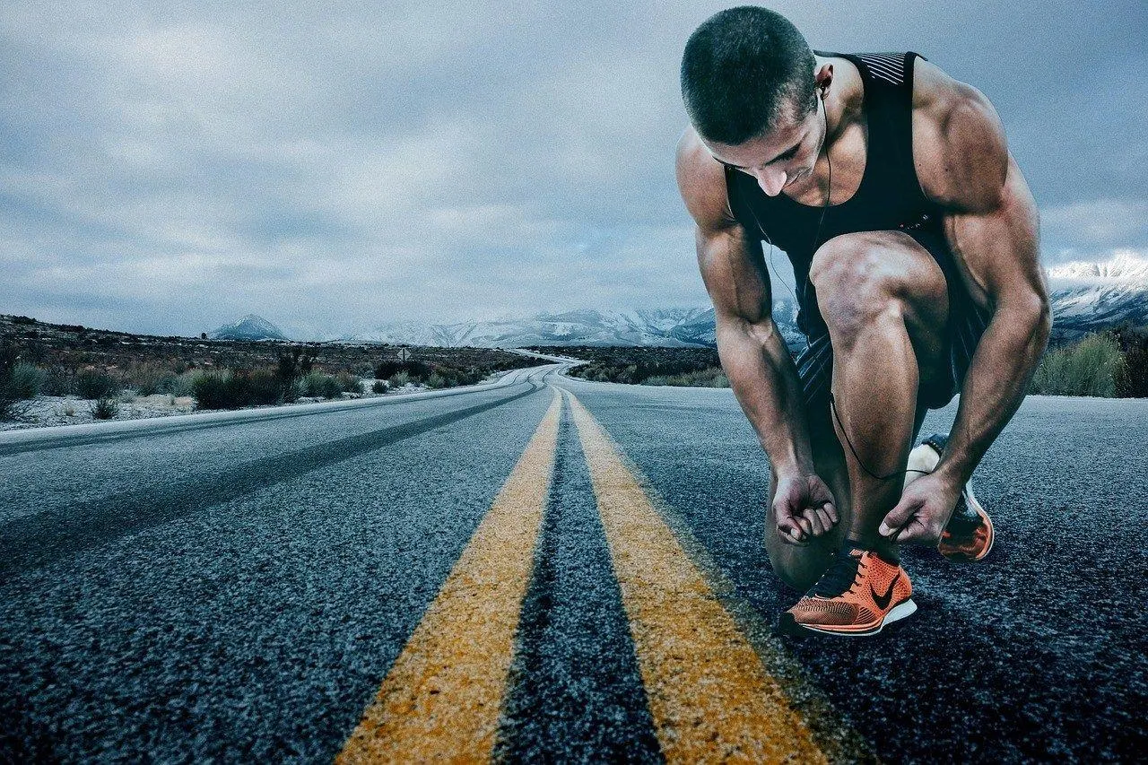 Runner Crouching To Tie Shoes on an Open Road Before Workout
