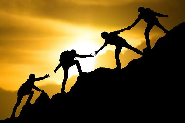 Silhouette of Climbers Helping Each Other At Sunset