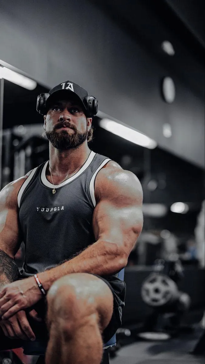 Strong Muscular Man Resting on a Gym Bench Between Workouts