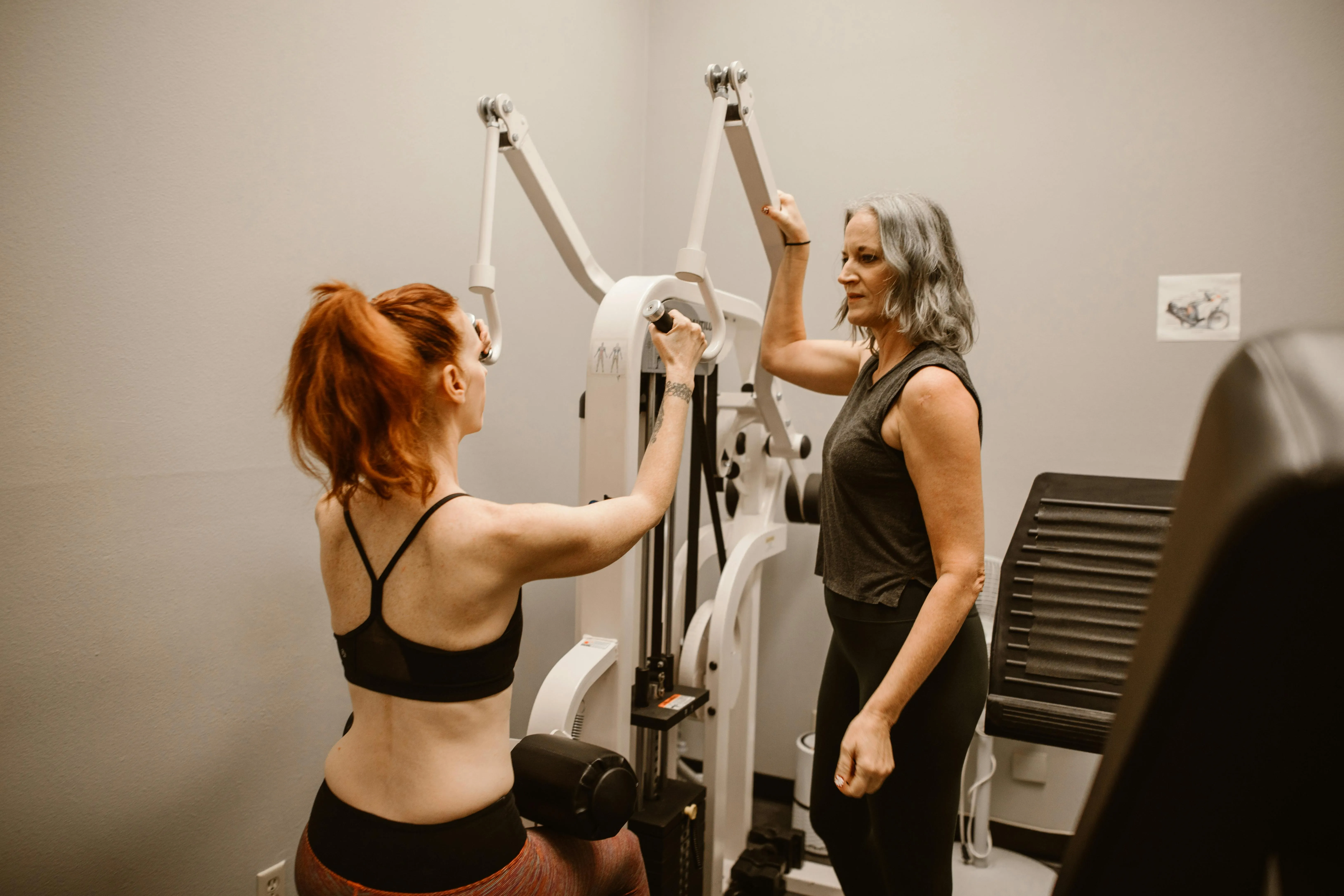 Trainer Helping Client With Gym Machine Workout Routine