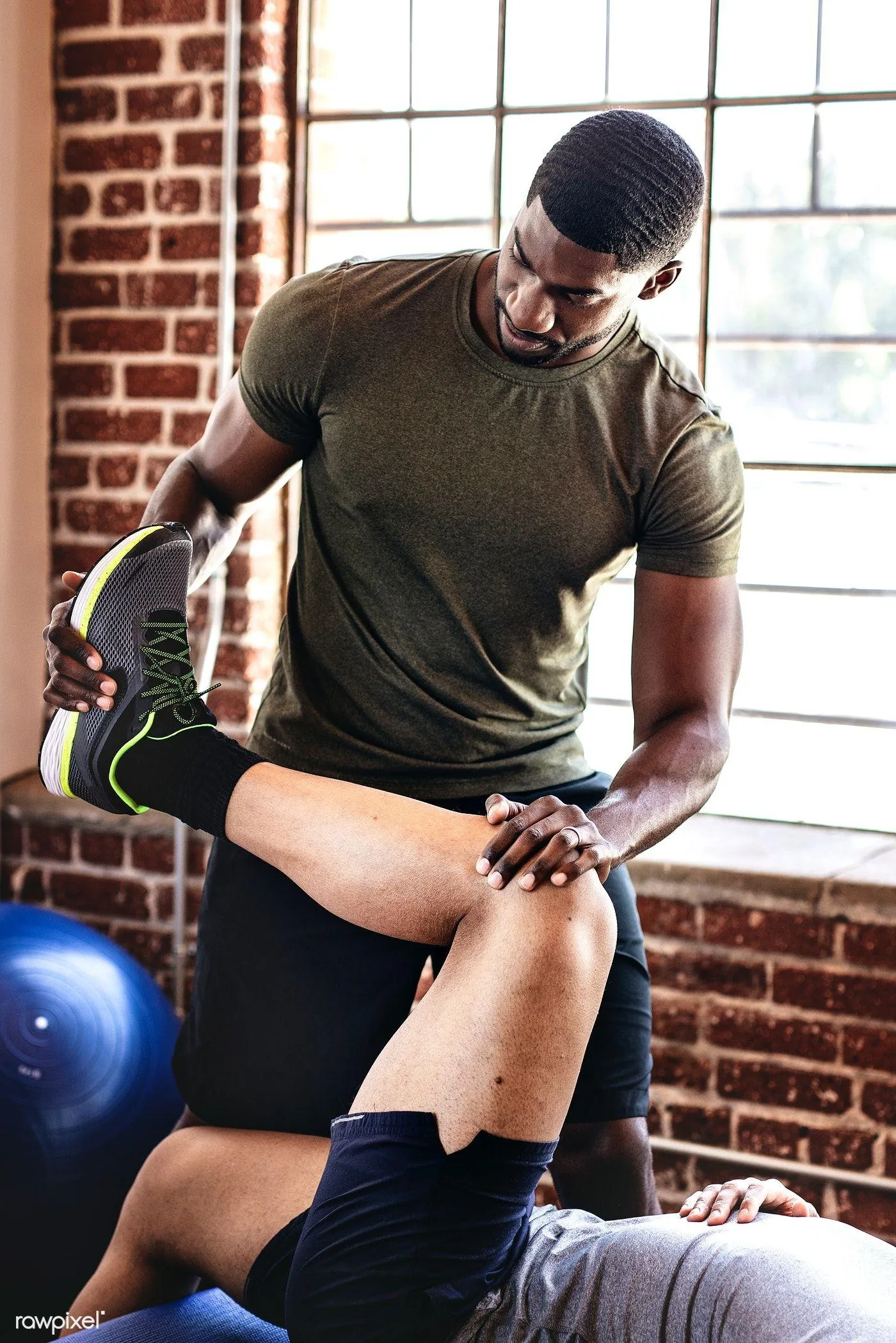 Trainer Helping a Man Stretch in the Gym For a Leg Workout