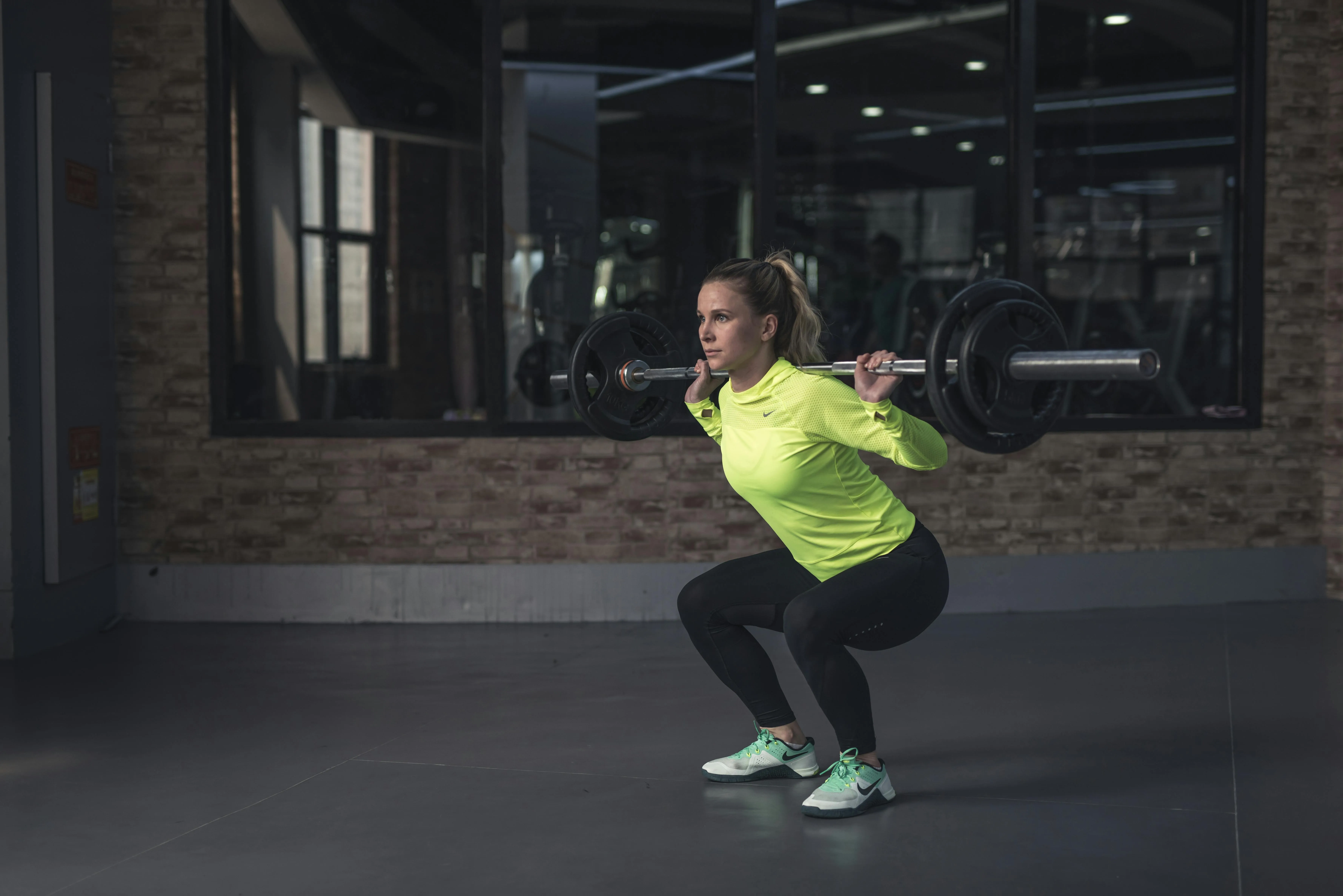 Woman Doing Barbell Squat Exercise in a Modern Indoor Gym