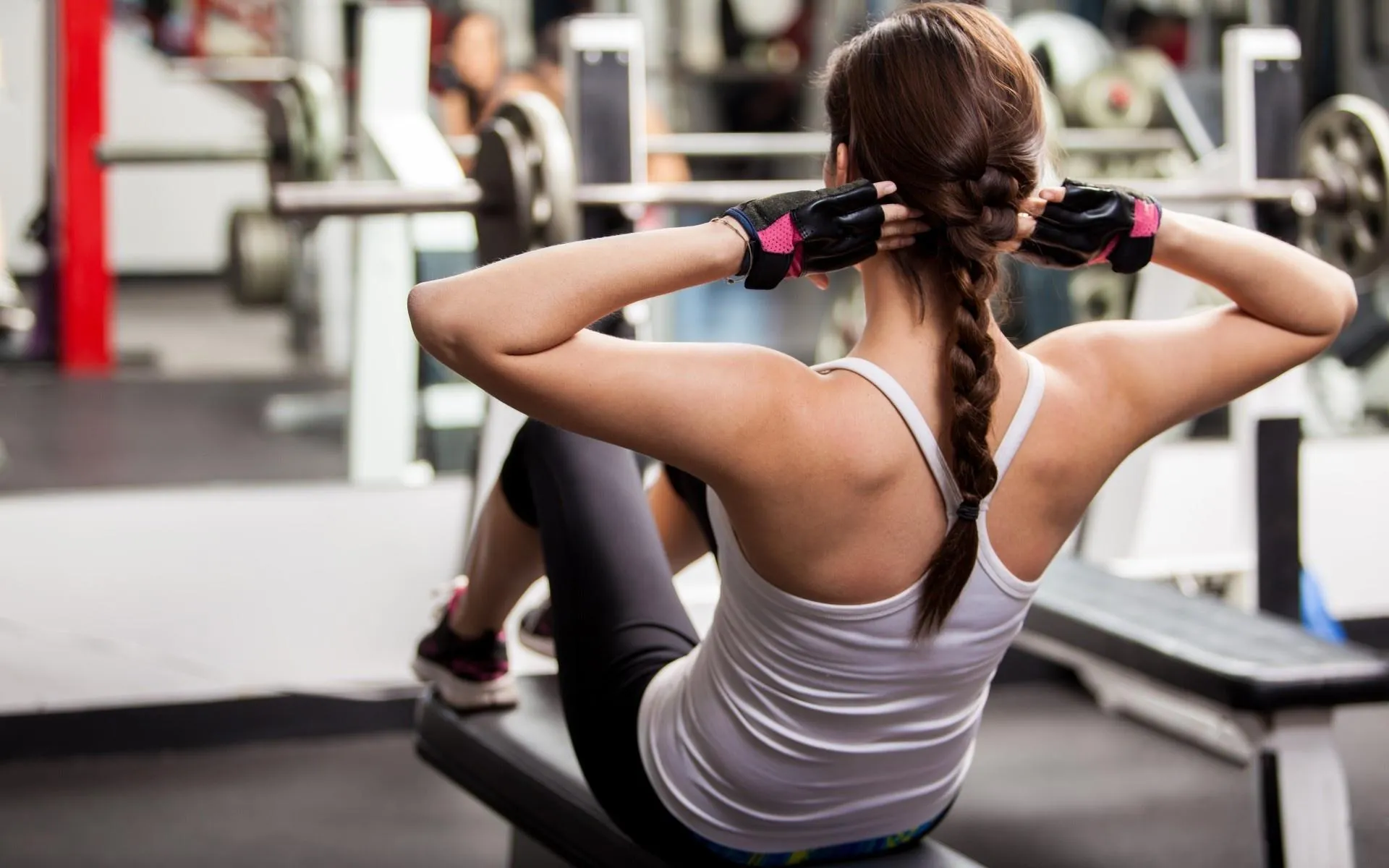 Woman Doing Sit Ups With Hands Behind Head in the Gym