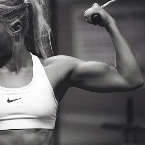 Woman Flexing Her Bicep Muscle Wearing a White Sports Top