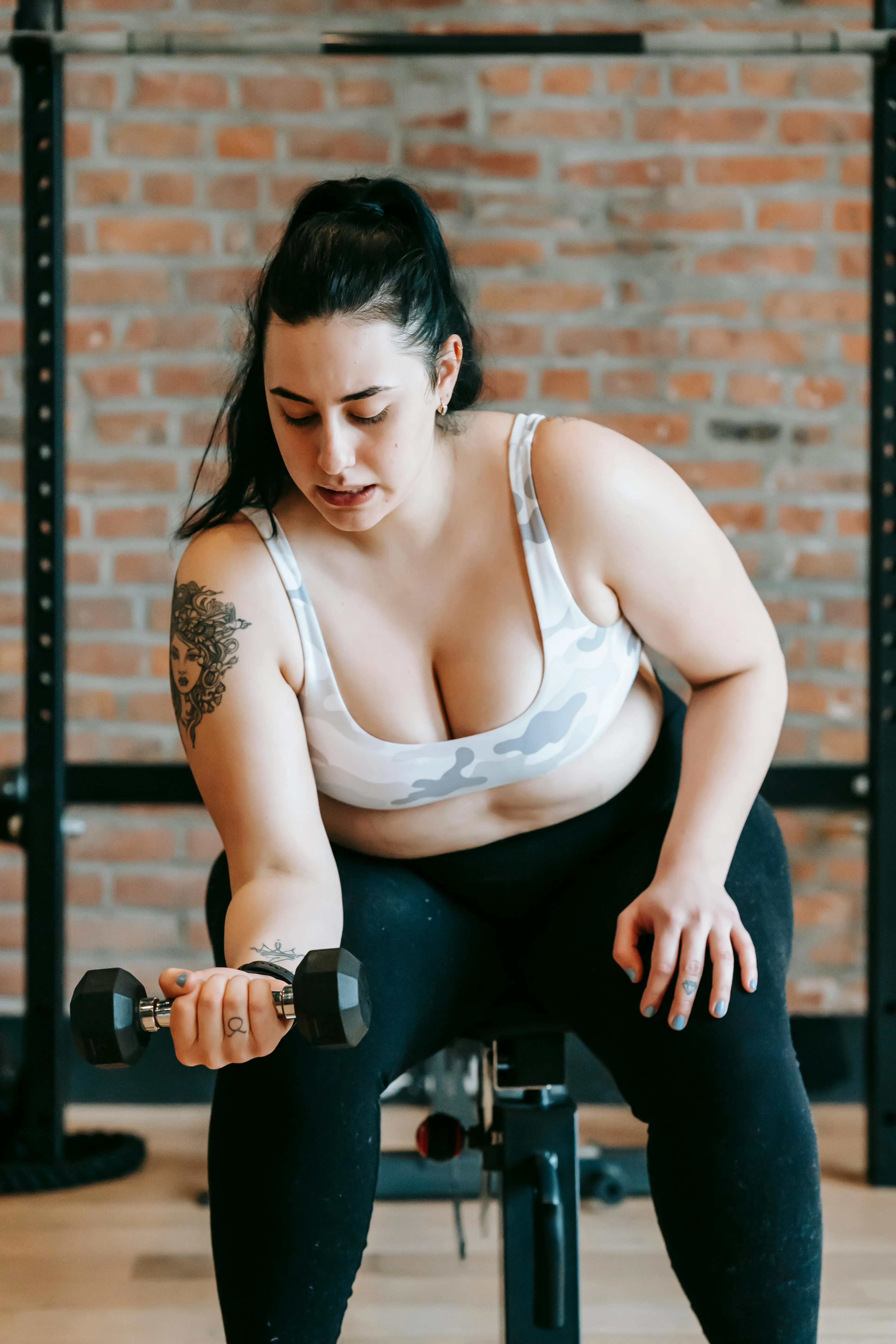 Woman Focusing on Arm Curls Using a Dumbbell At the Gym