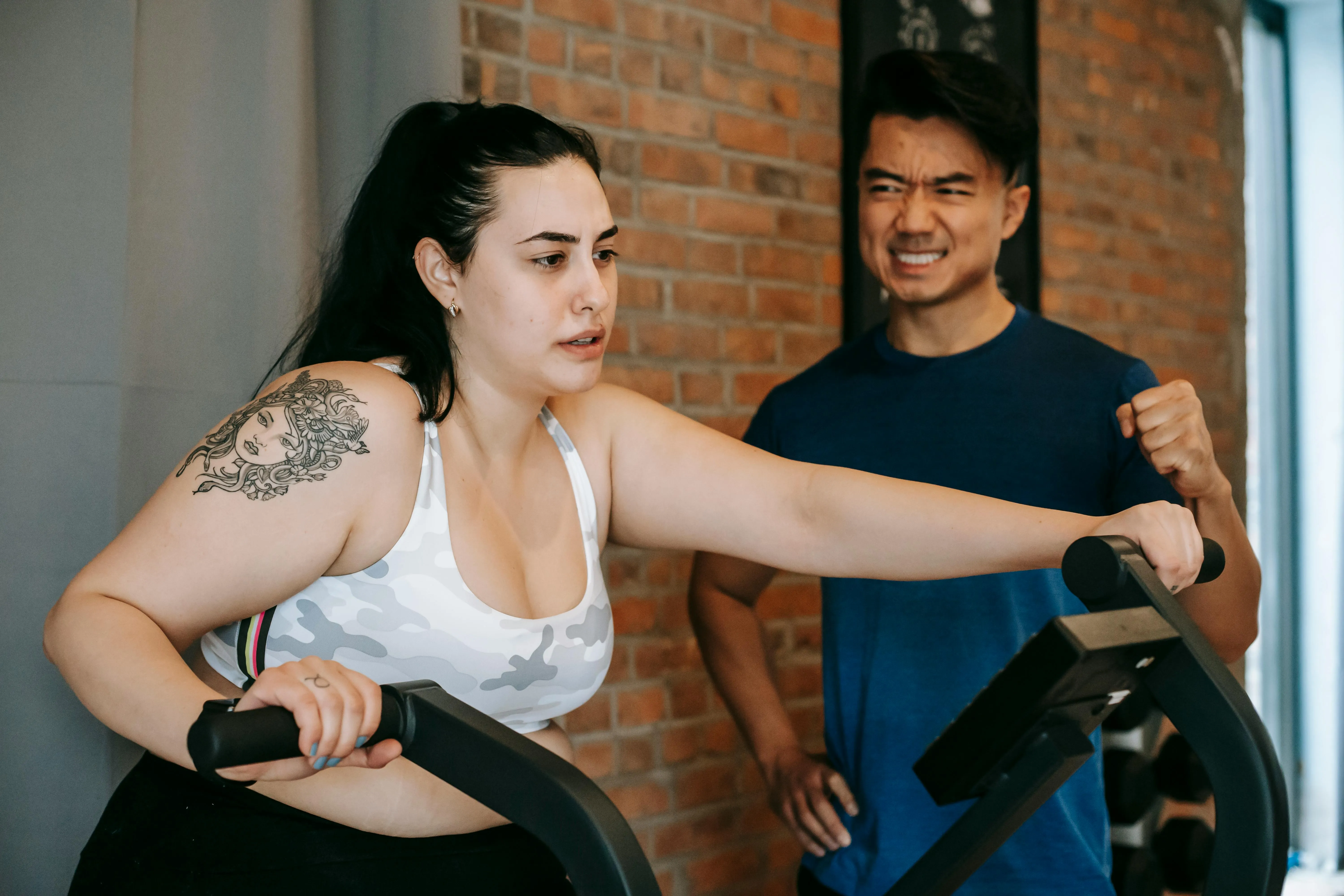Woman Getting Assistance With Workout Form in the Gym