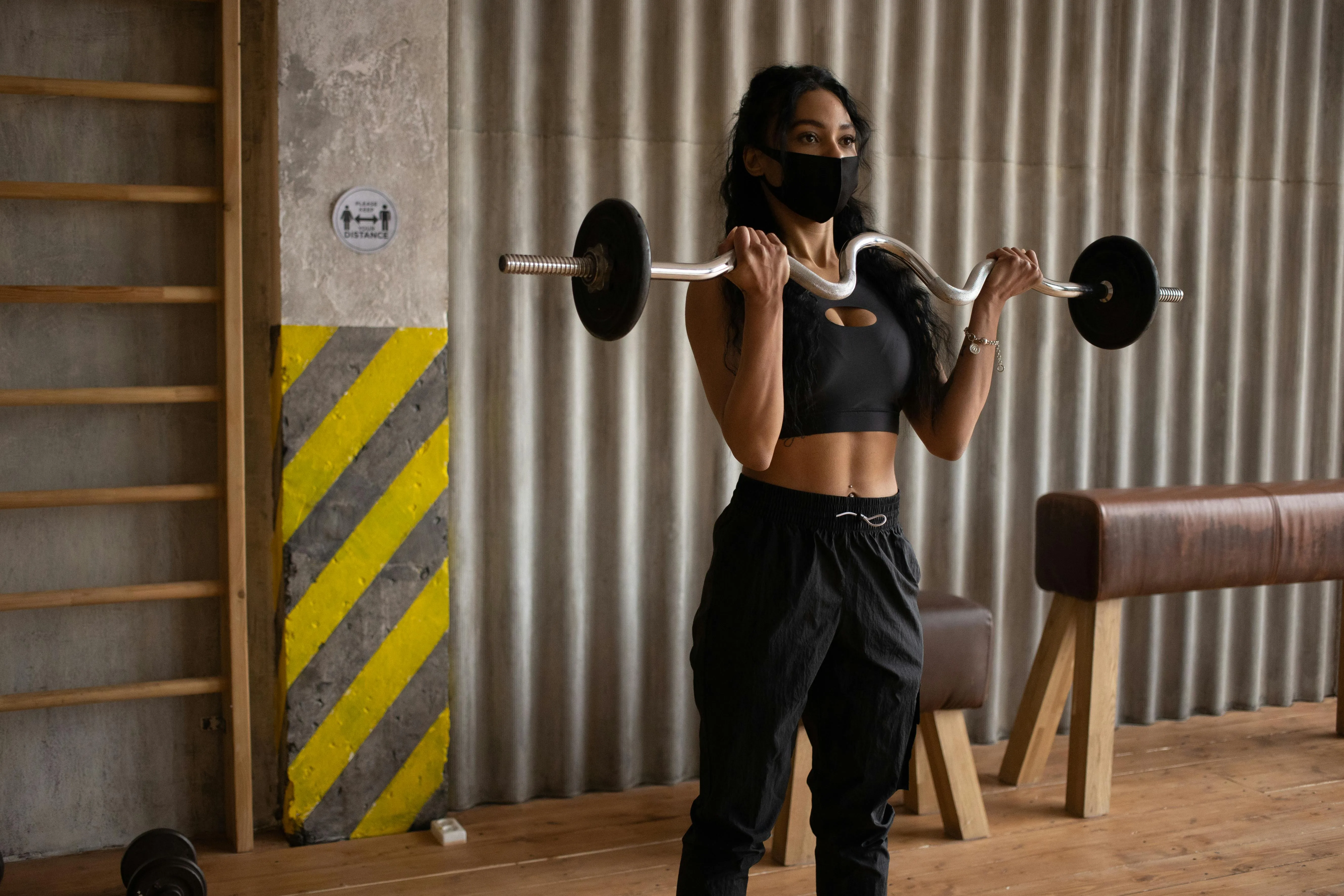 Woman Lifting Barbell Weights Wearing Mask For Safety in Gym