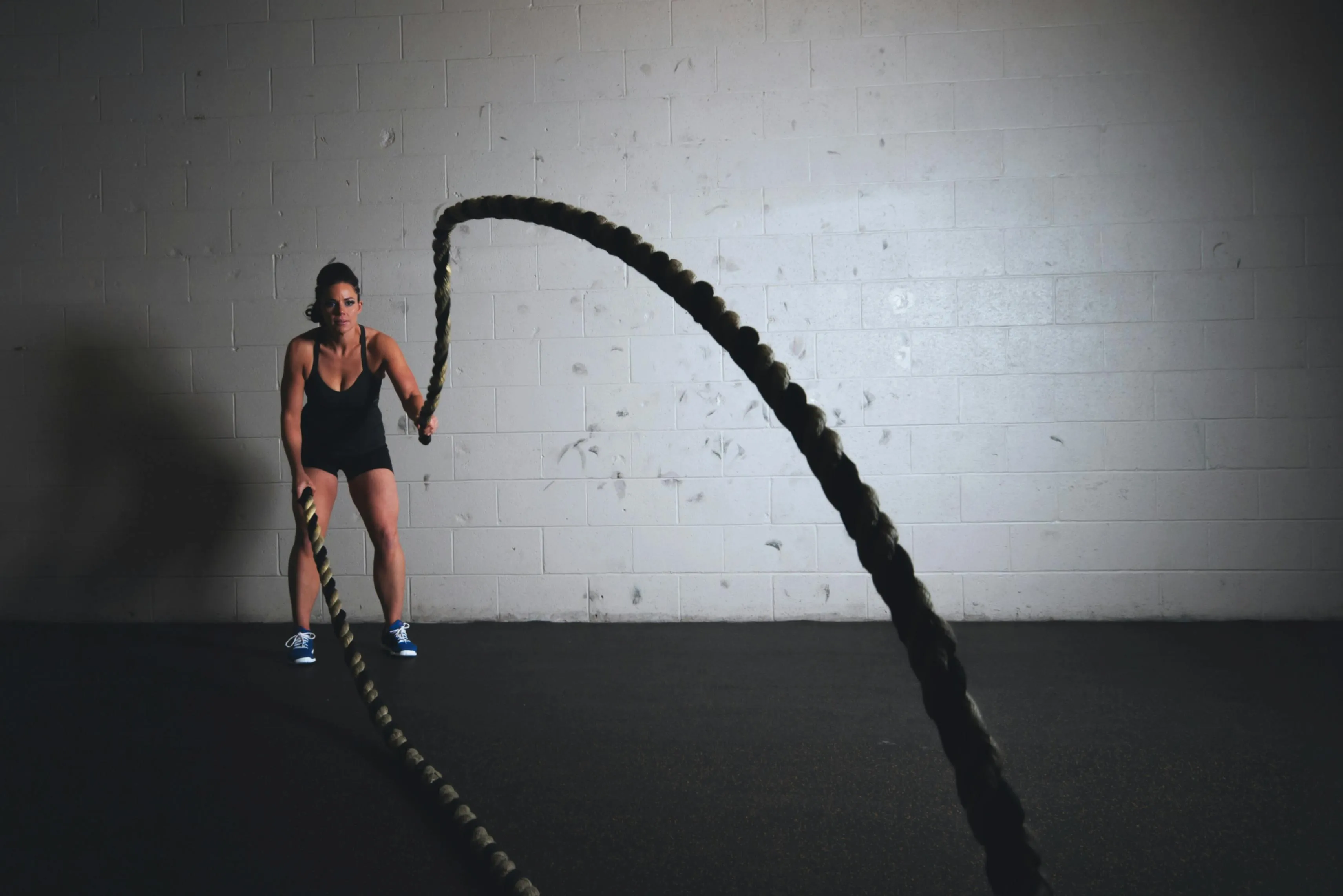 Woman Using Battle Ropes For High Intensity Gym Exercise
