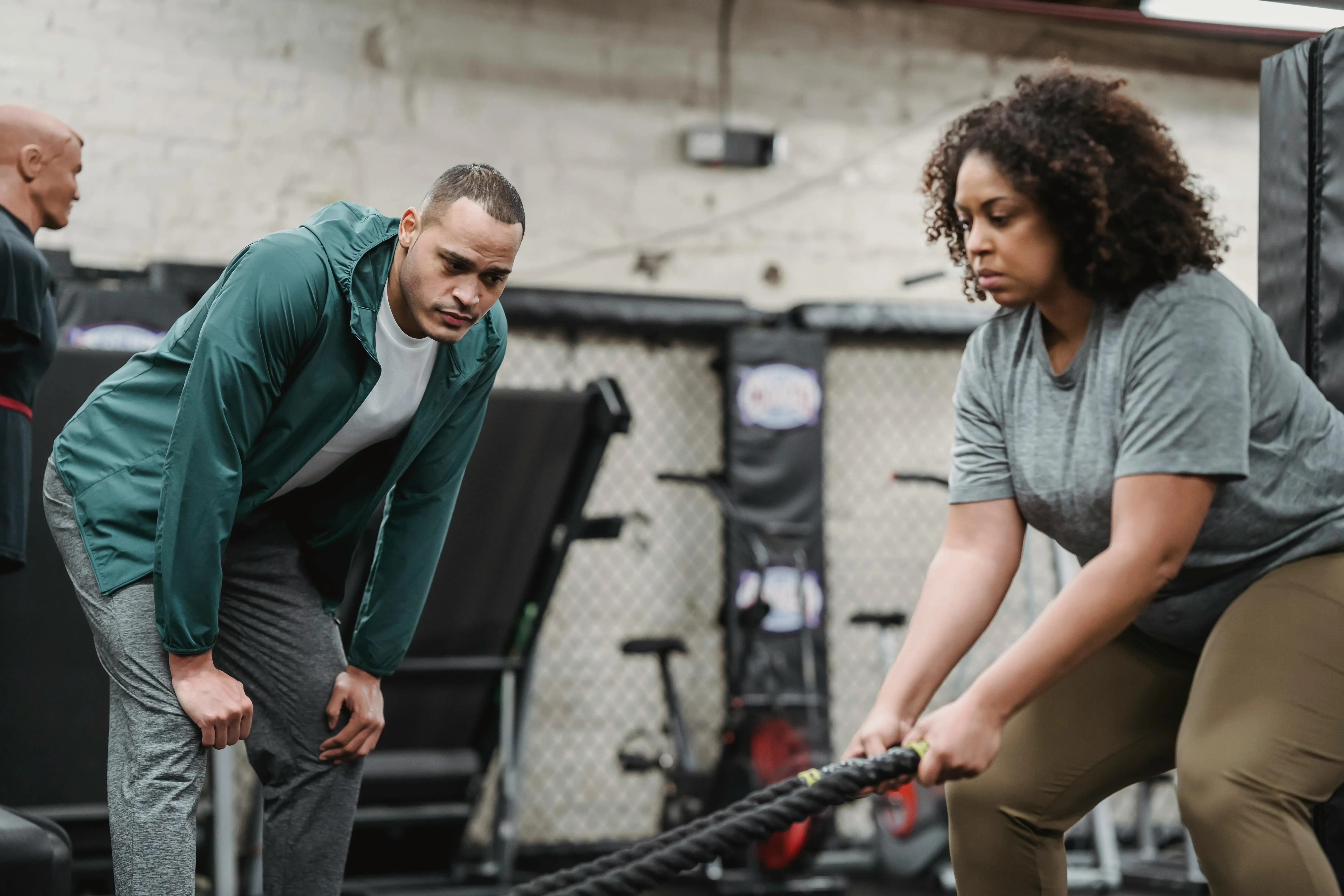 Woman Using Battle Ropes While Trainer Gives Focused Support