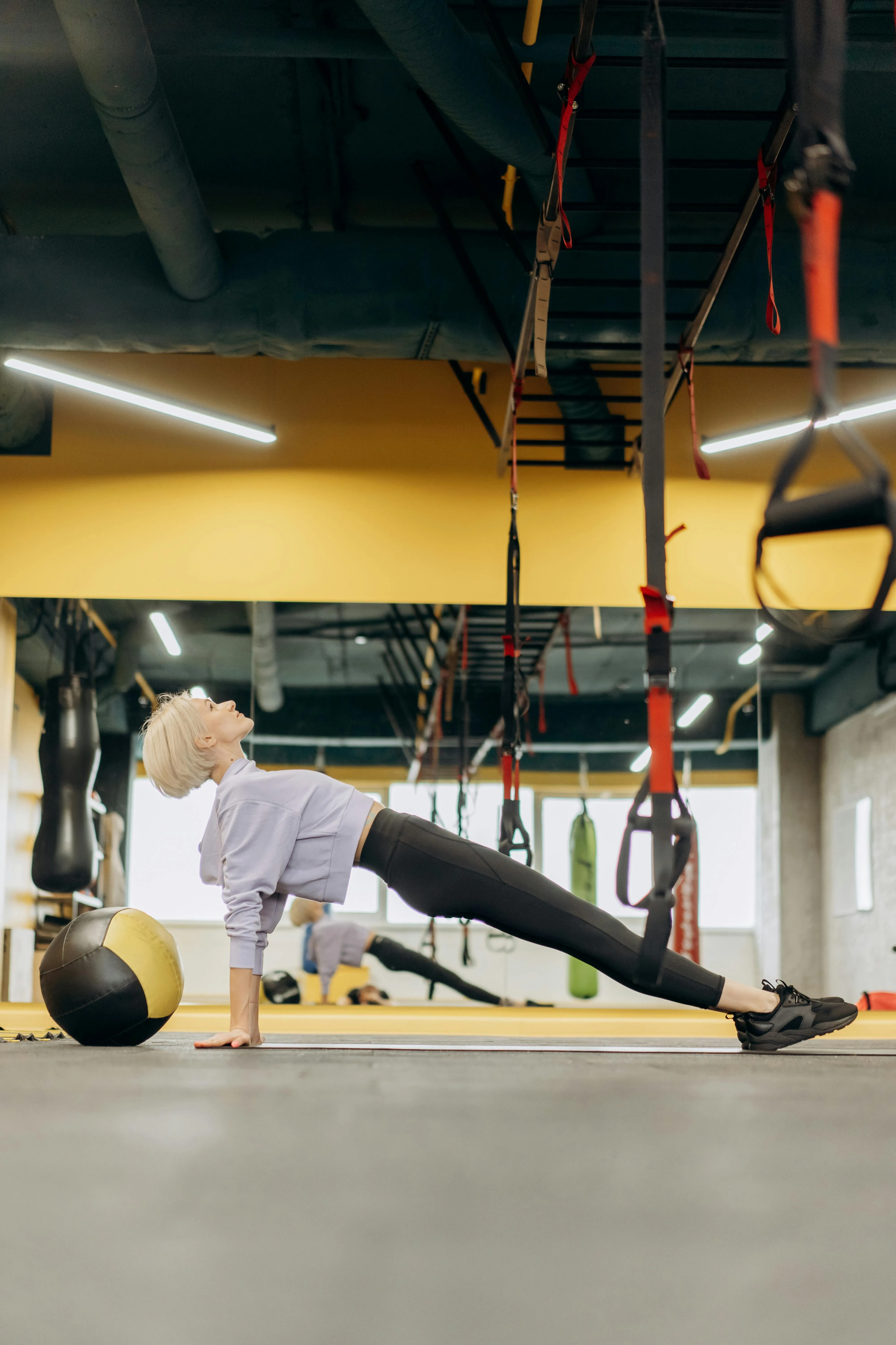 Women Stretching Using Trx Suspension Straps in Workout Area