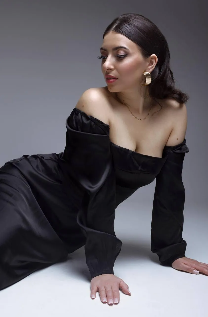Artist photo of a woman in black robe dress sitting on floor