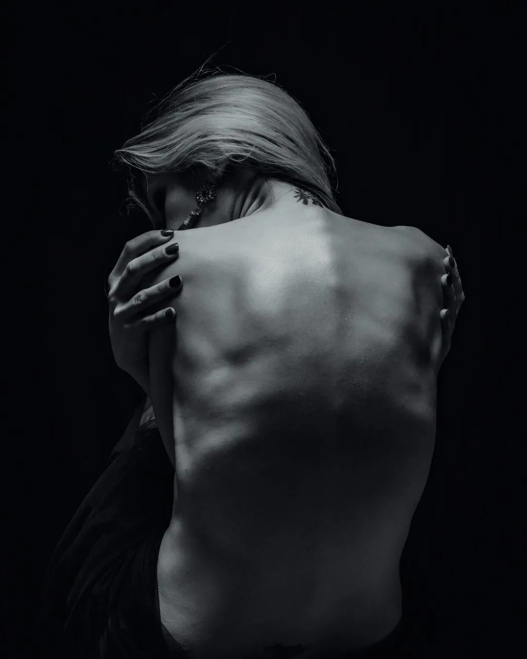 Artistic dark portrait of a woman with her back exposed