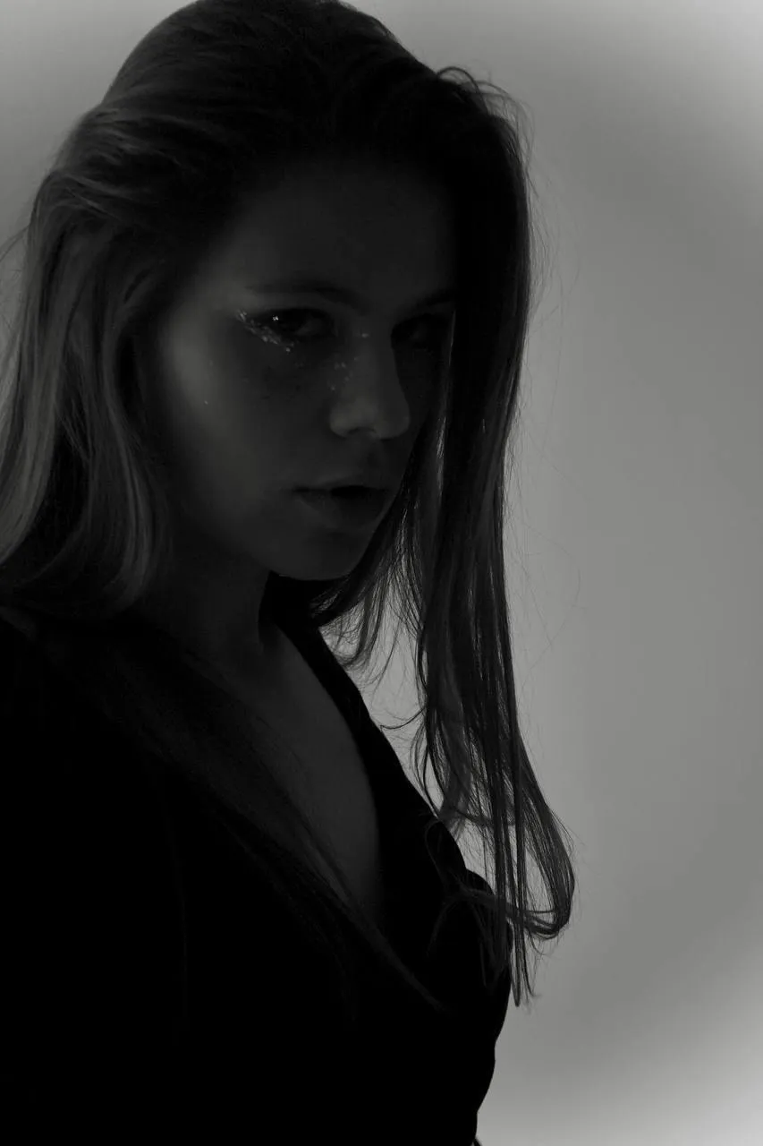 Artistic portrait of woman in dark light with glitter makeup