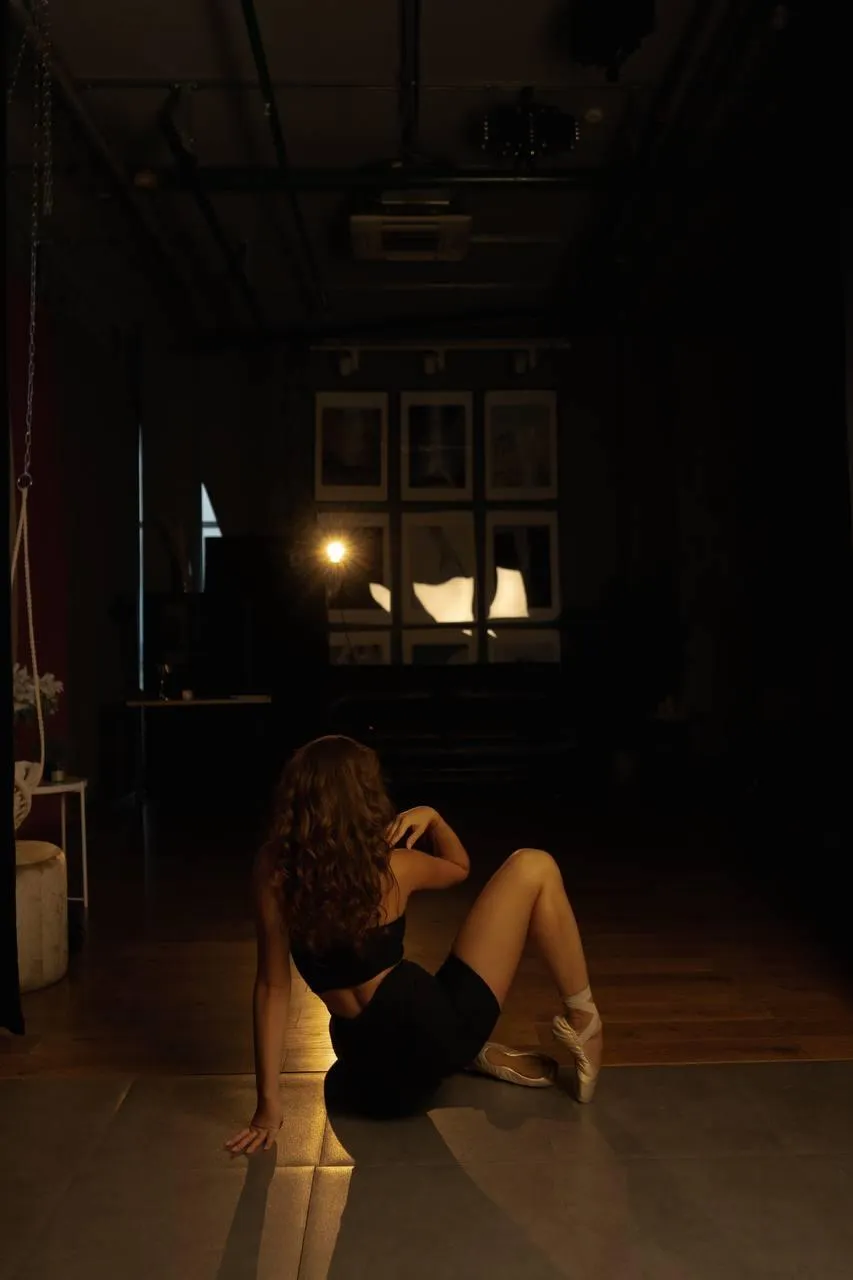 Artistic pose of a woman sitting on the floor in a dark room