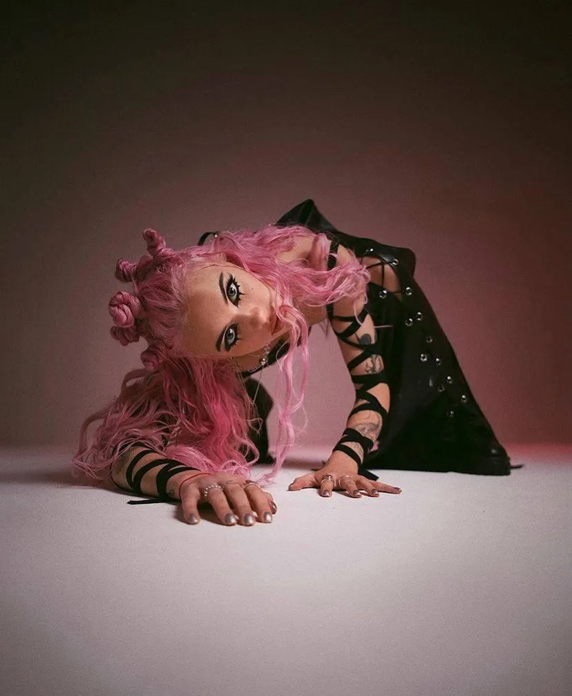 Artistic pose of woman with pink hair on white studio floor