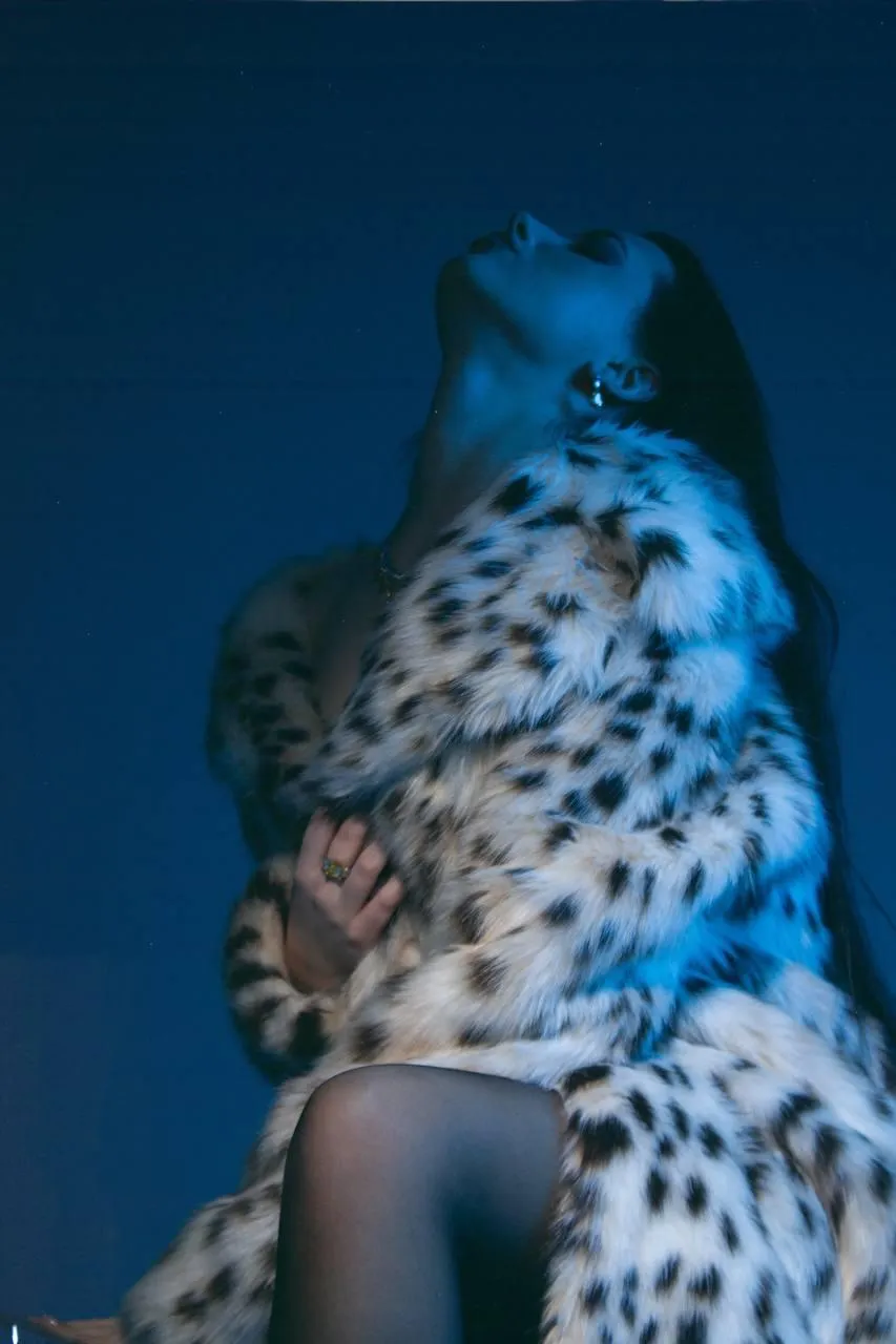 Artistic shot of a woman in a fur coat under blue lighting